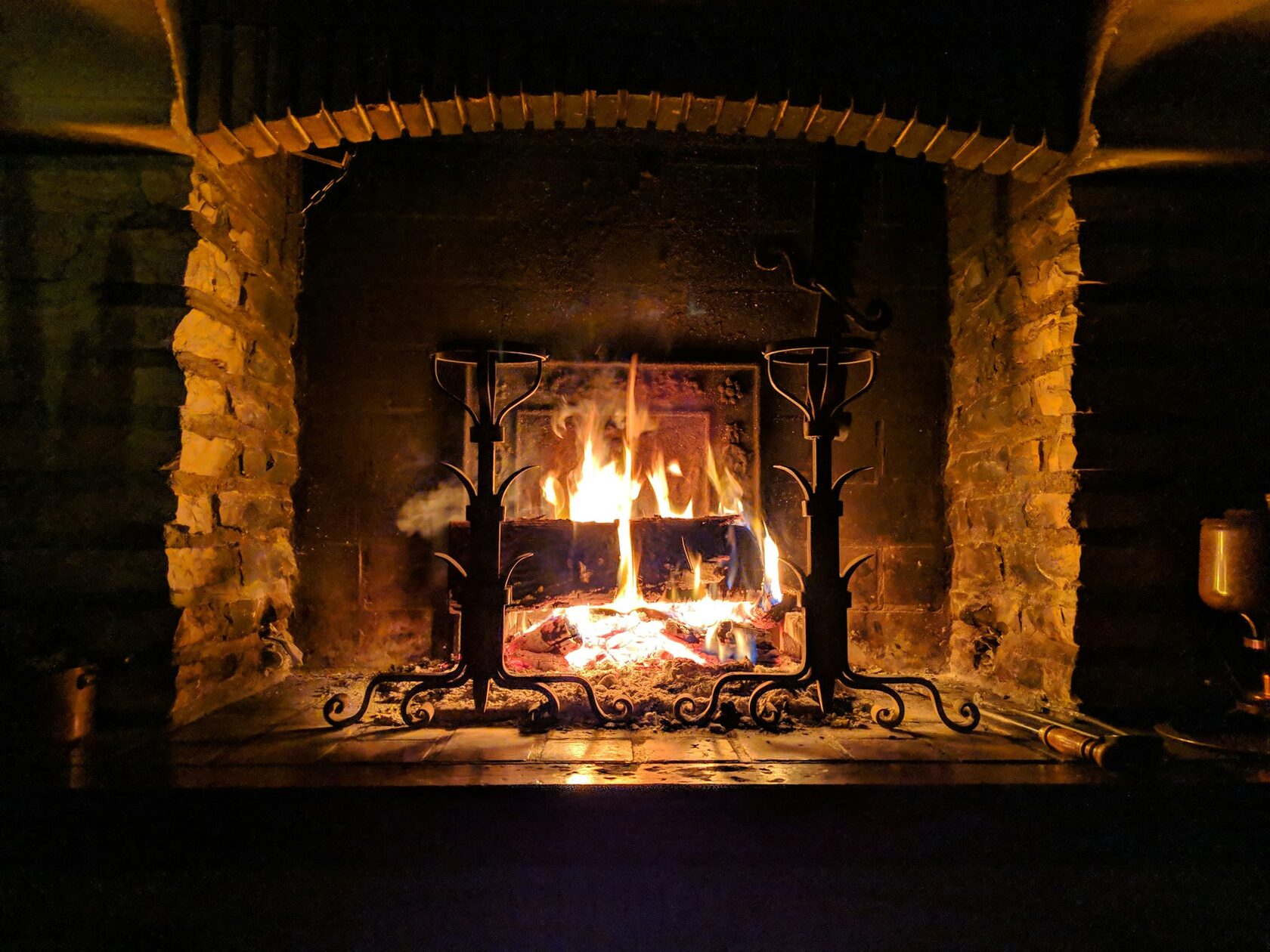 Close-up of a fiddler's hands playing beside a glowing open fire, a pint of stout on the table.