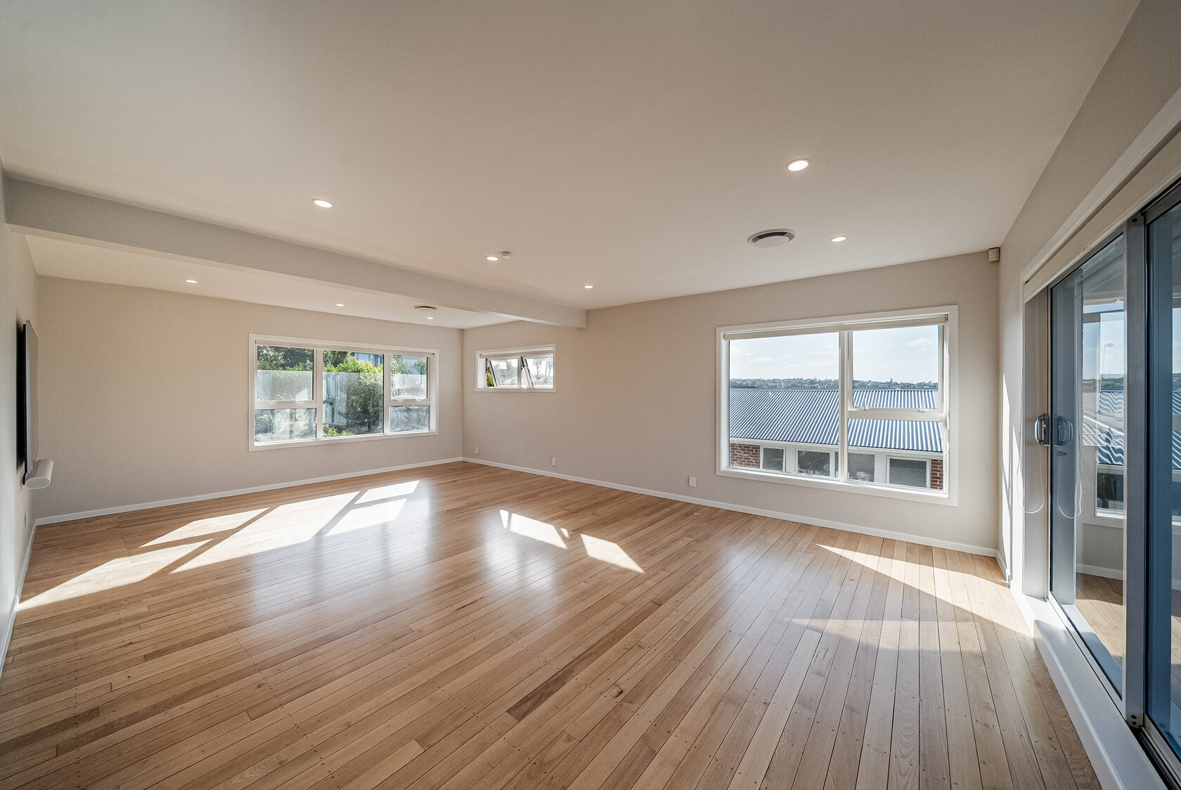 Renovated Glenfield family living room with timber floor, white walls and wide windows
