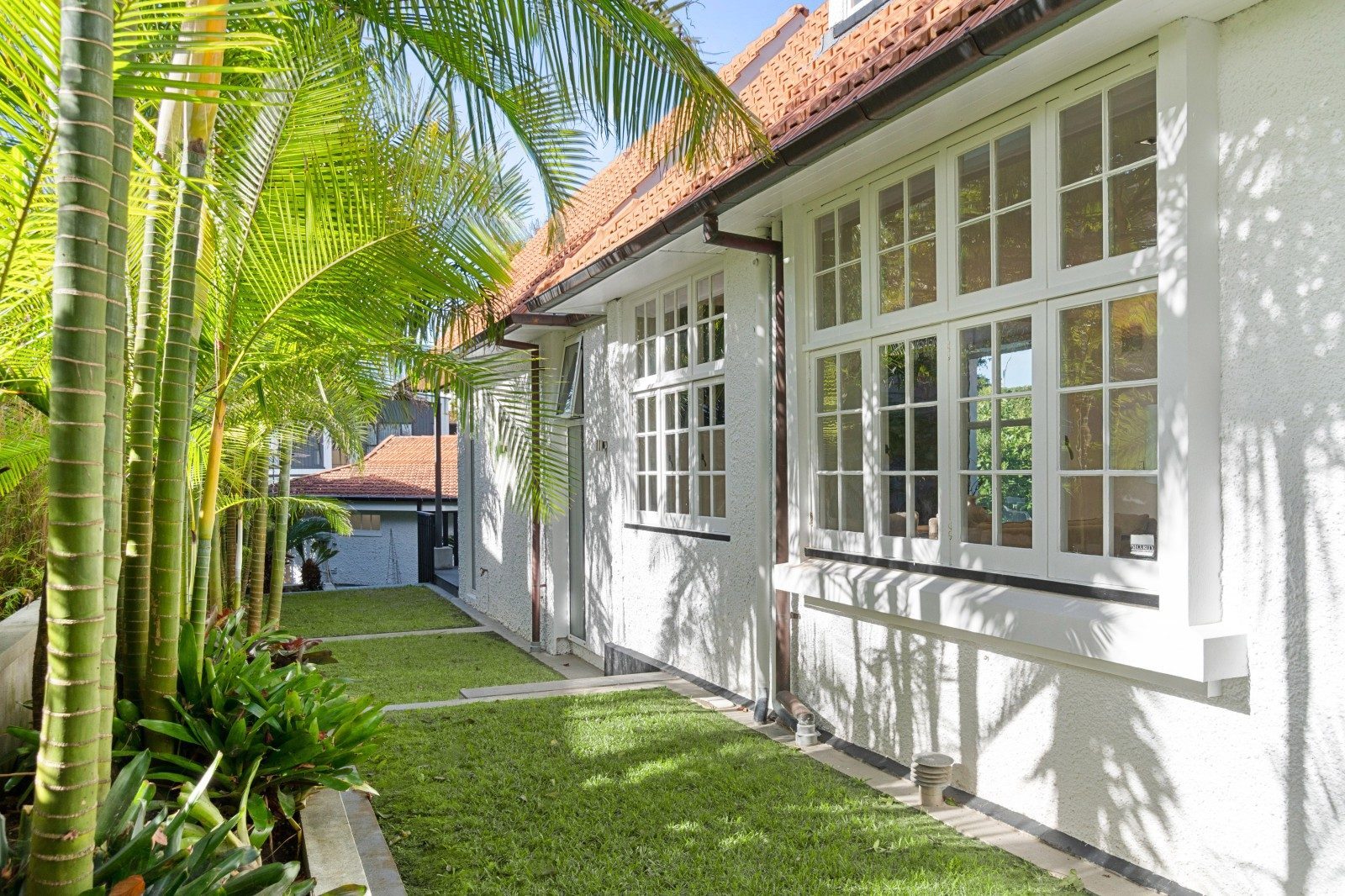 Garden and lawn beside the white exterior and leadlight windows of the Owens Road home