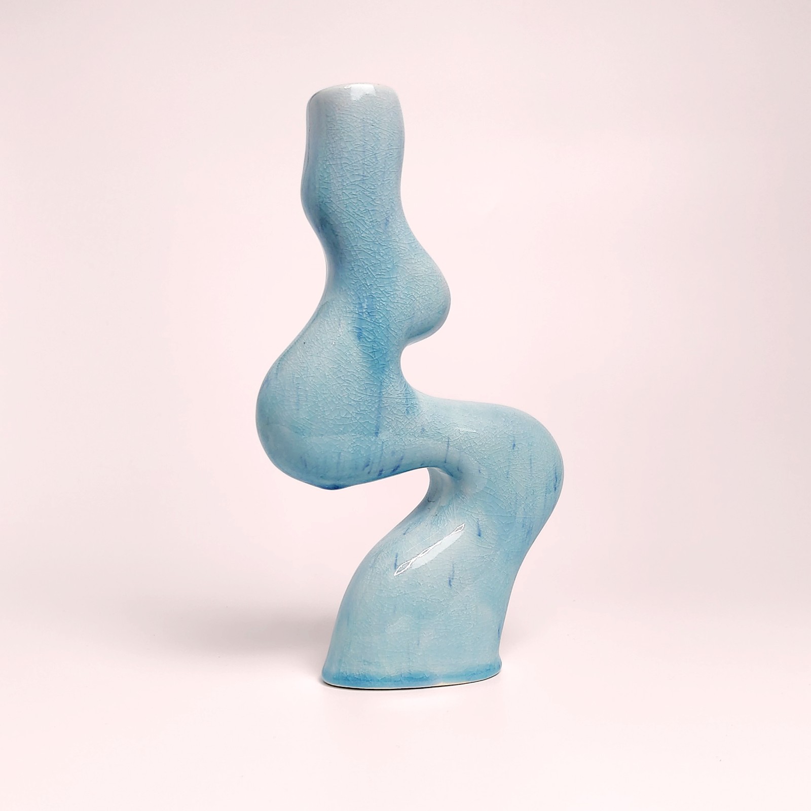 Unique handmade sculptural ceramic candle holder featuring a flowing wavy form and glossy blue glaze, designed for a single tall candle