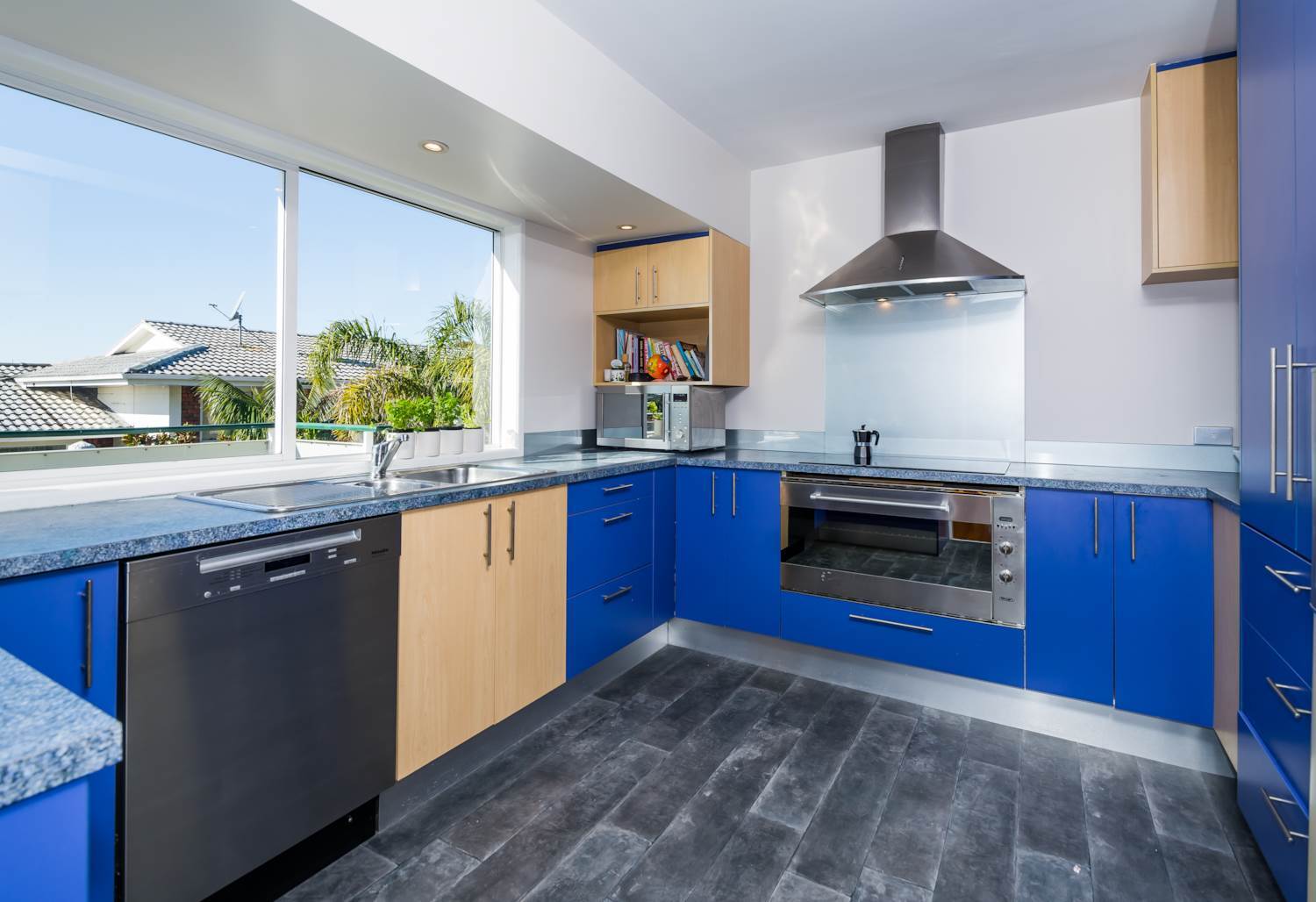 Glenfield kitchen before renovation with blue and timber cabinetry, a corner cooking area and a wide window