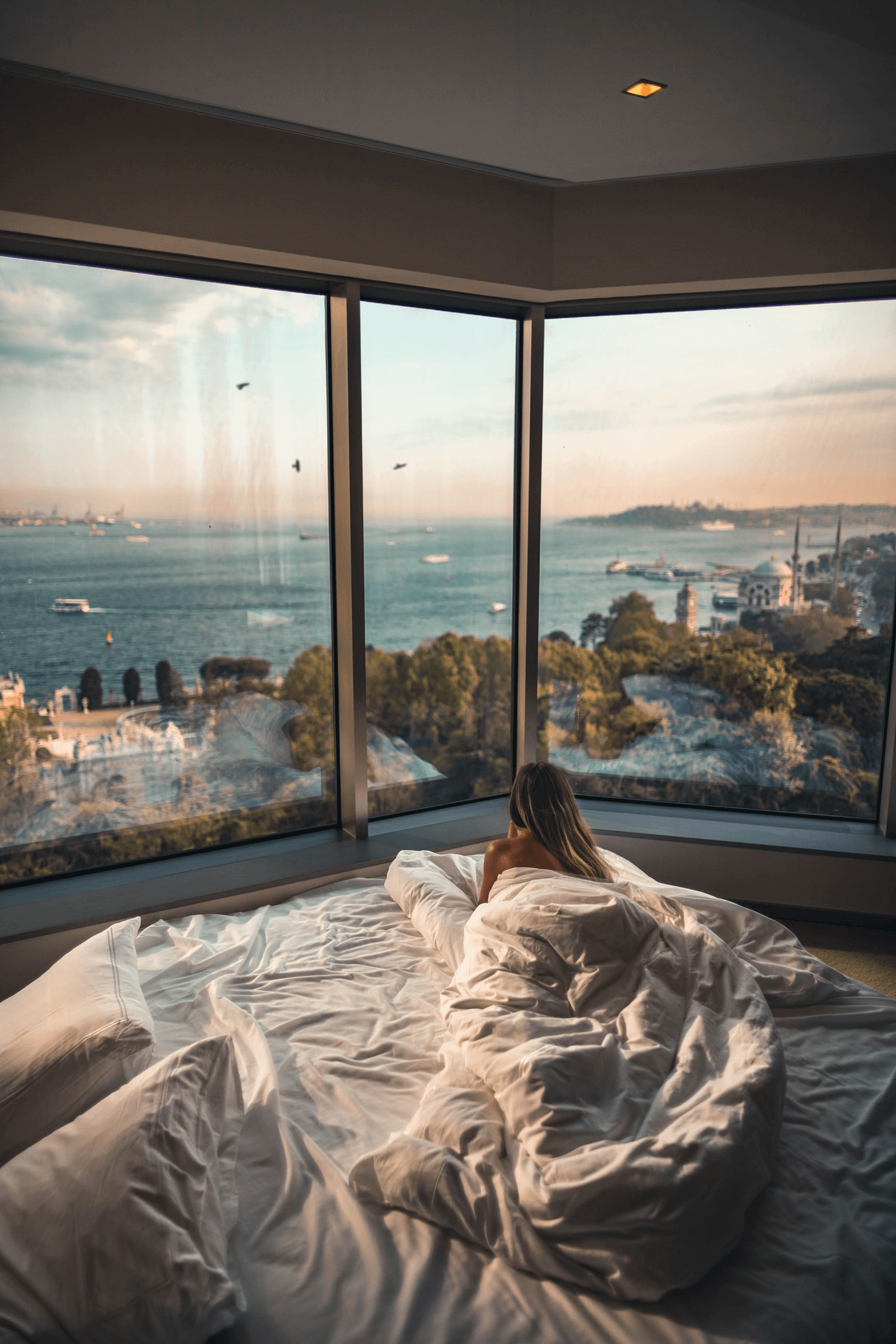 a woman is laying in bed with a view of the ocean, real estate loans