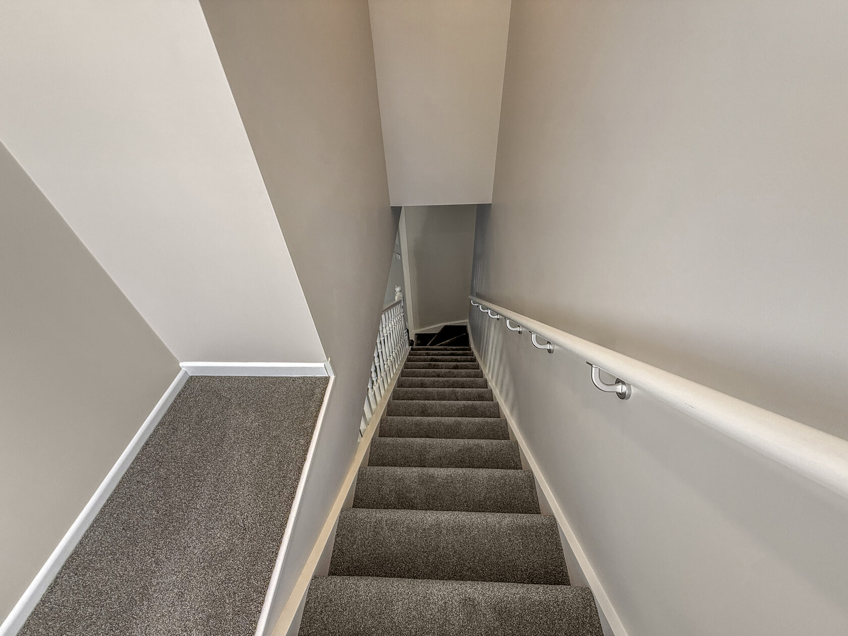 Carpeted stairwell with white handrails in the renovated bungalow