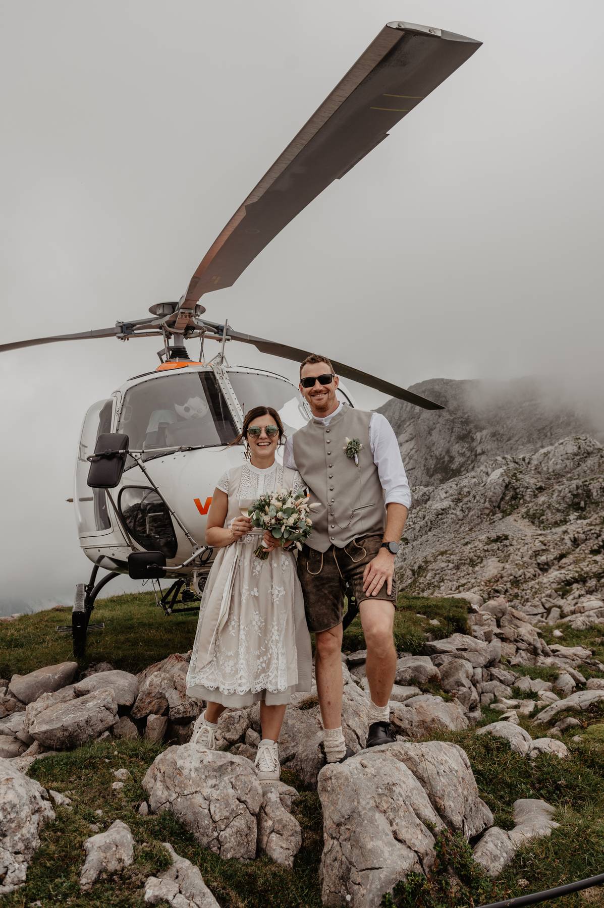 Adventurous elopement in Europe — couple posing with helicopter in the Alps for a bold, unforgettable wedding experience.