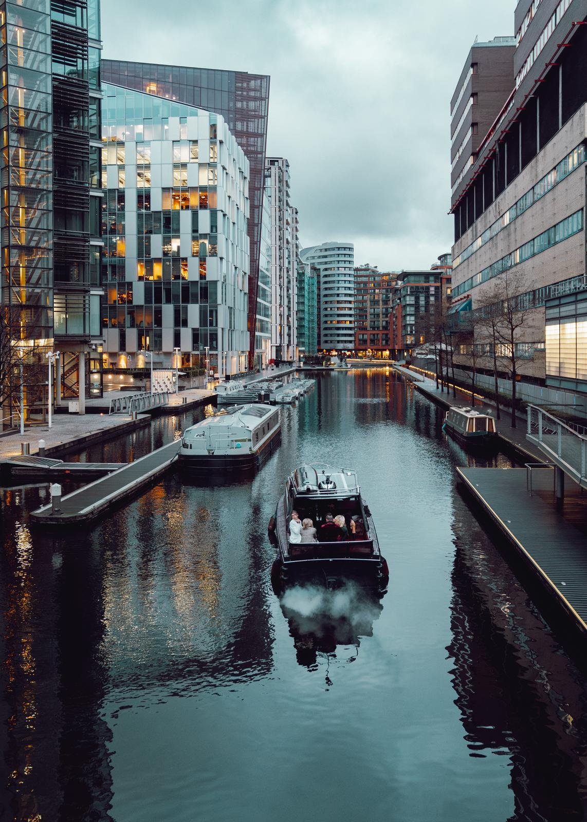 Private boat gliding through London canal at sunset