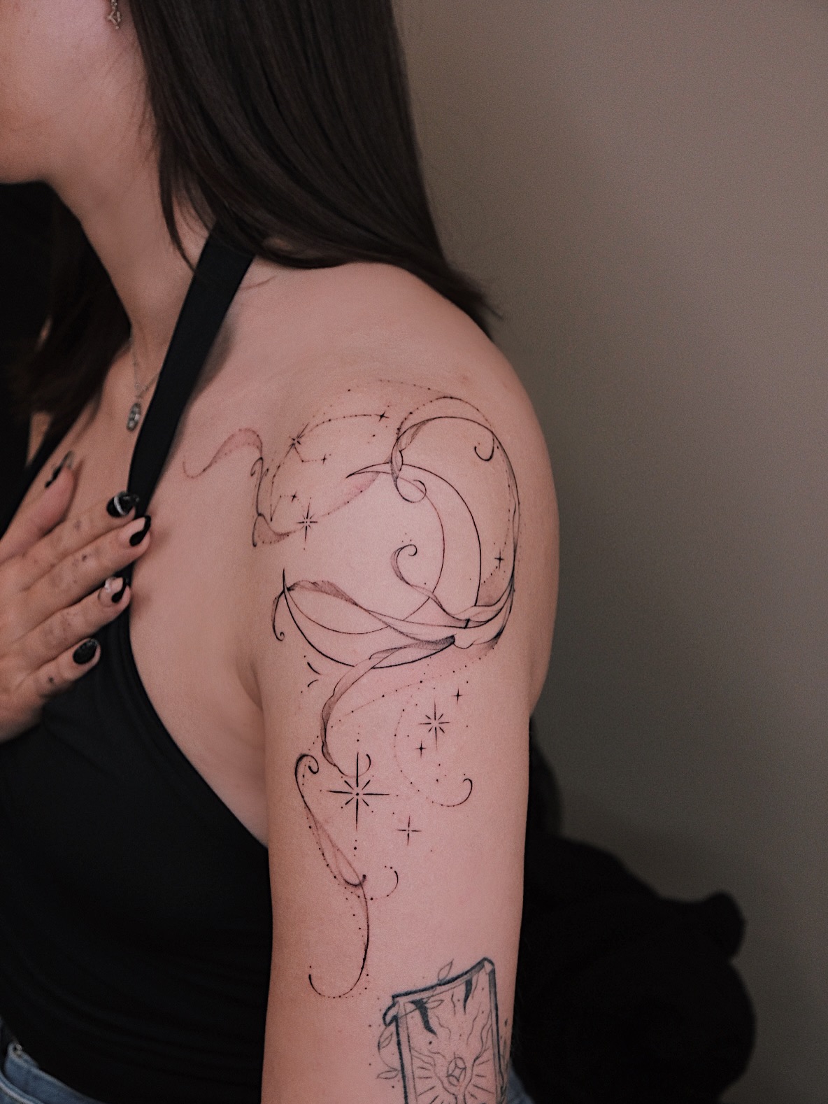 Abstract fine line tattoo with curved lines, dots and stars across the shoulder and upper arm by Cathy