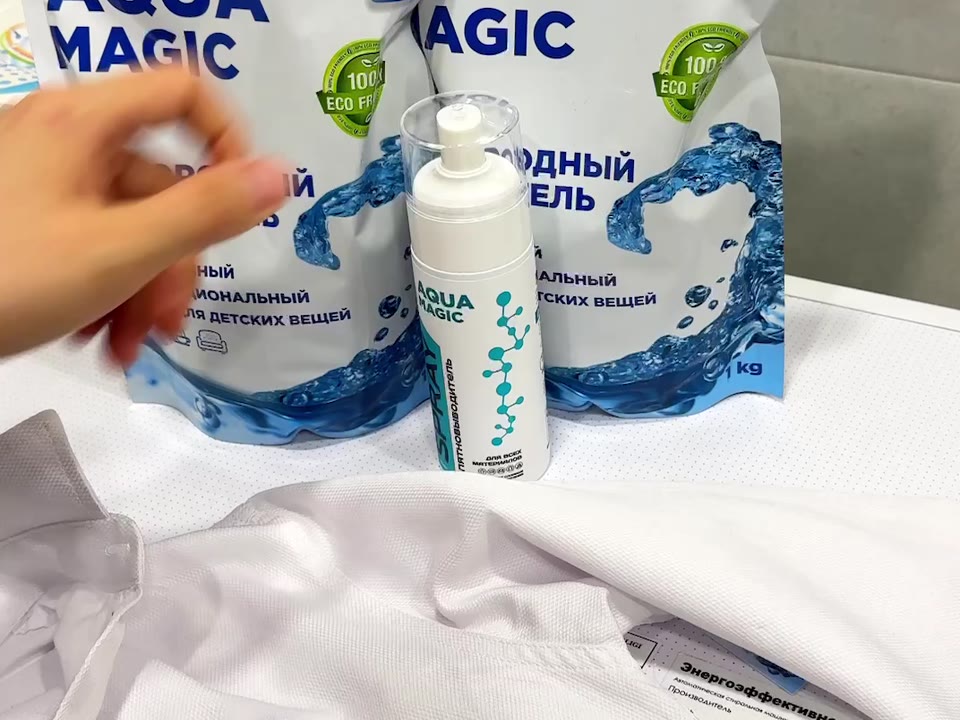 Спрей-пятновыводитель AQUA MAGIC с прозрачной крышкой рядом с белой рубашкой