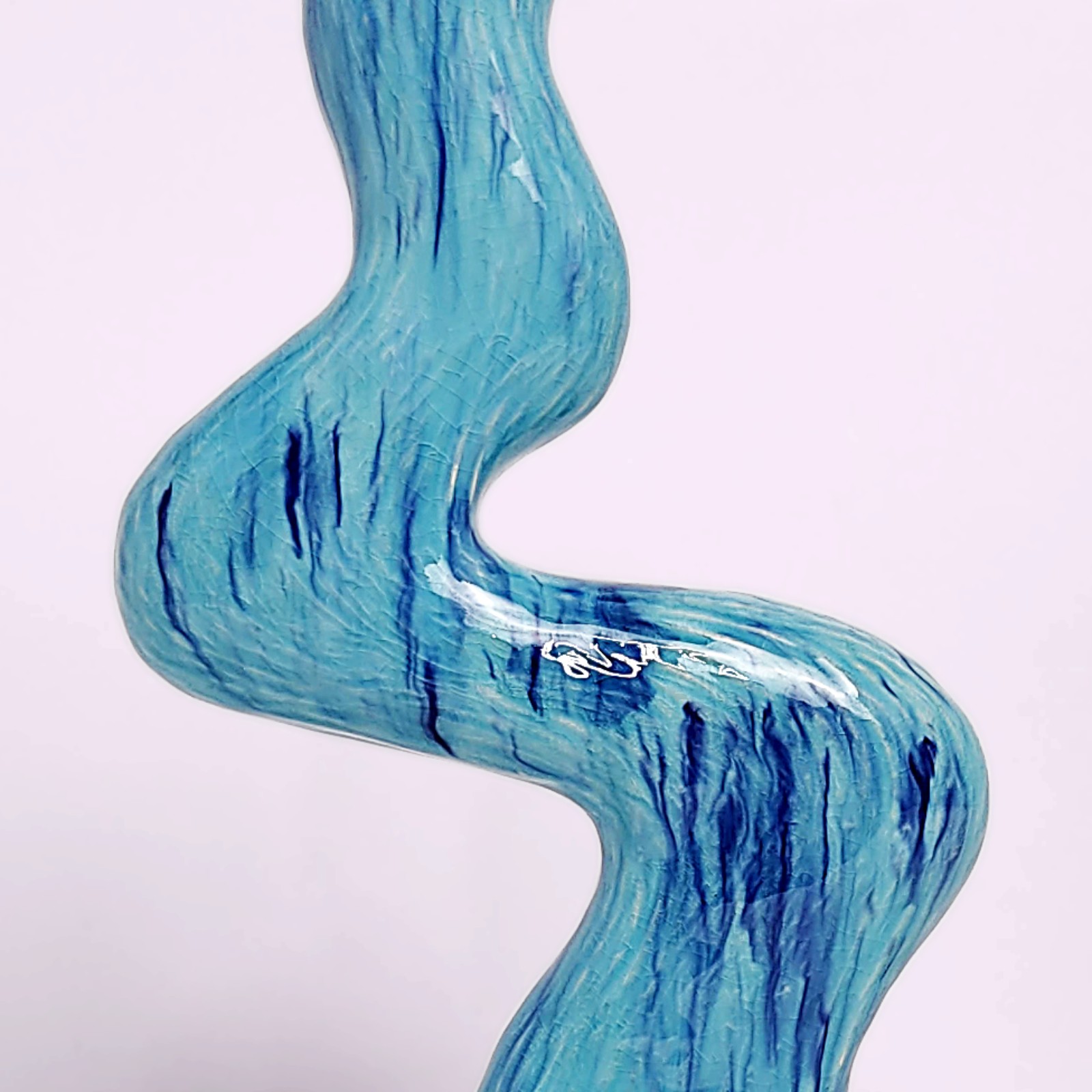 unique handmade ceramic candle holder for a single candle, featuring an organic wavy shape and blue glaze with watercolor-like drips