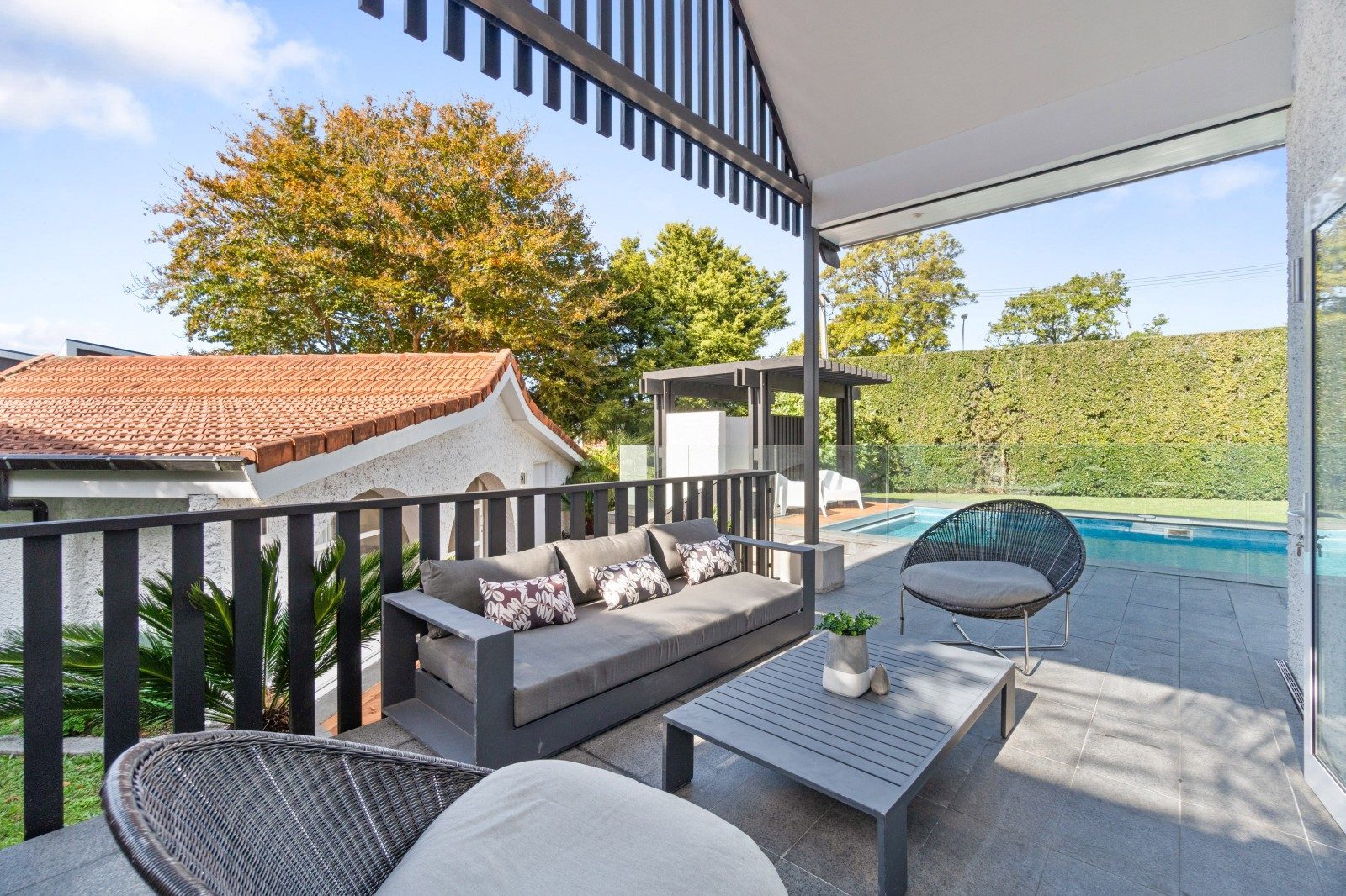 Covered balcony overlooking the landscaped garden and swimming pool in Epsom