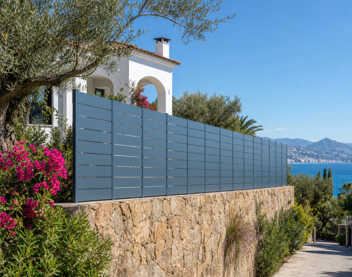 Modelo Maez de Kostum: valla de aluminio con lamas horizontales en azul sobre murete de piedra en una villa de la Costa del Sol, Málaga