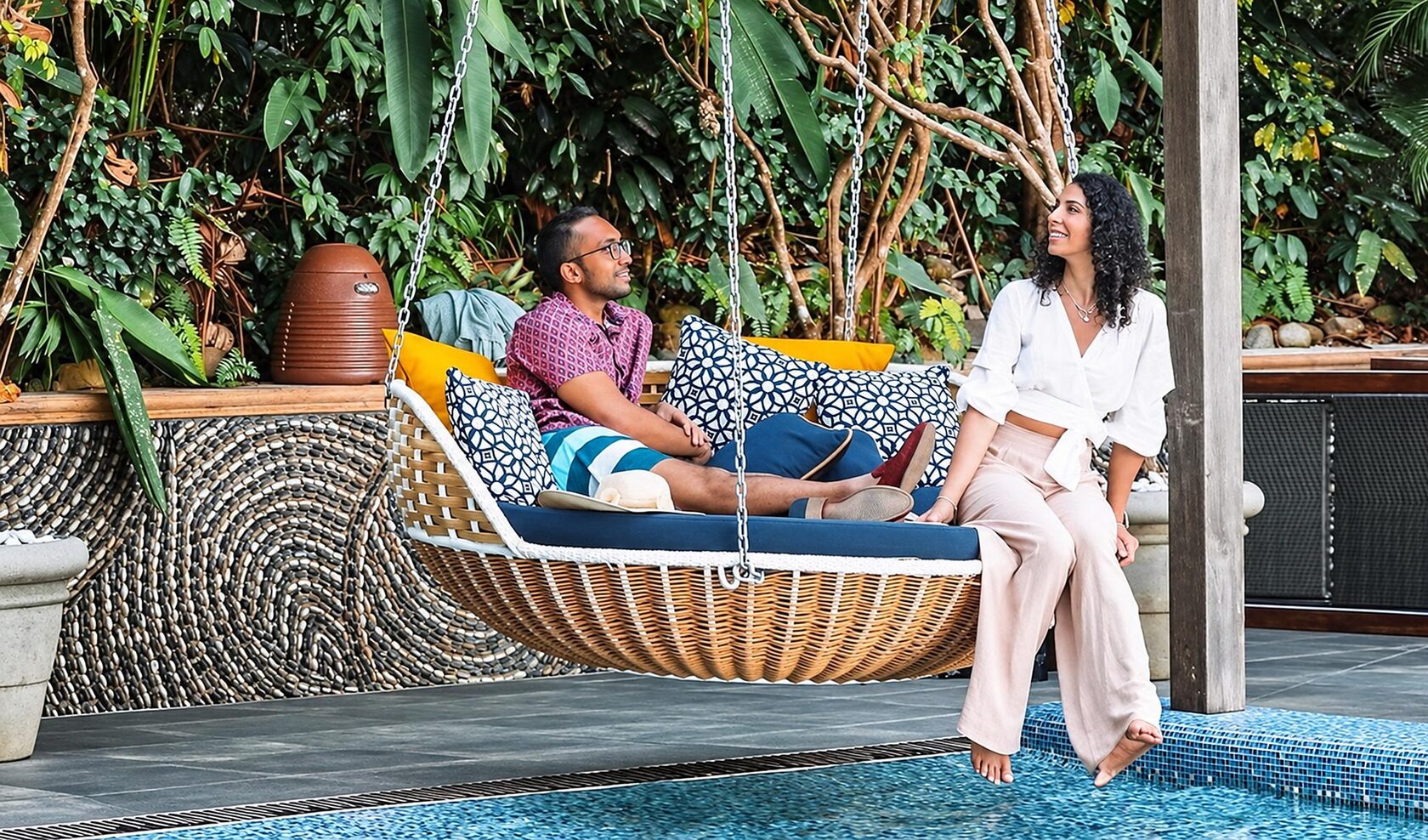 Couple relaxing on a hanging daybed by the pool, surrounded by tropical greenery at Hotel Makanda, Manuel Antonio