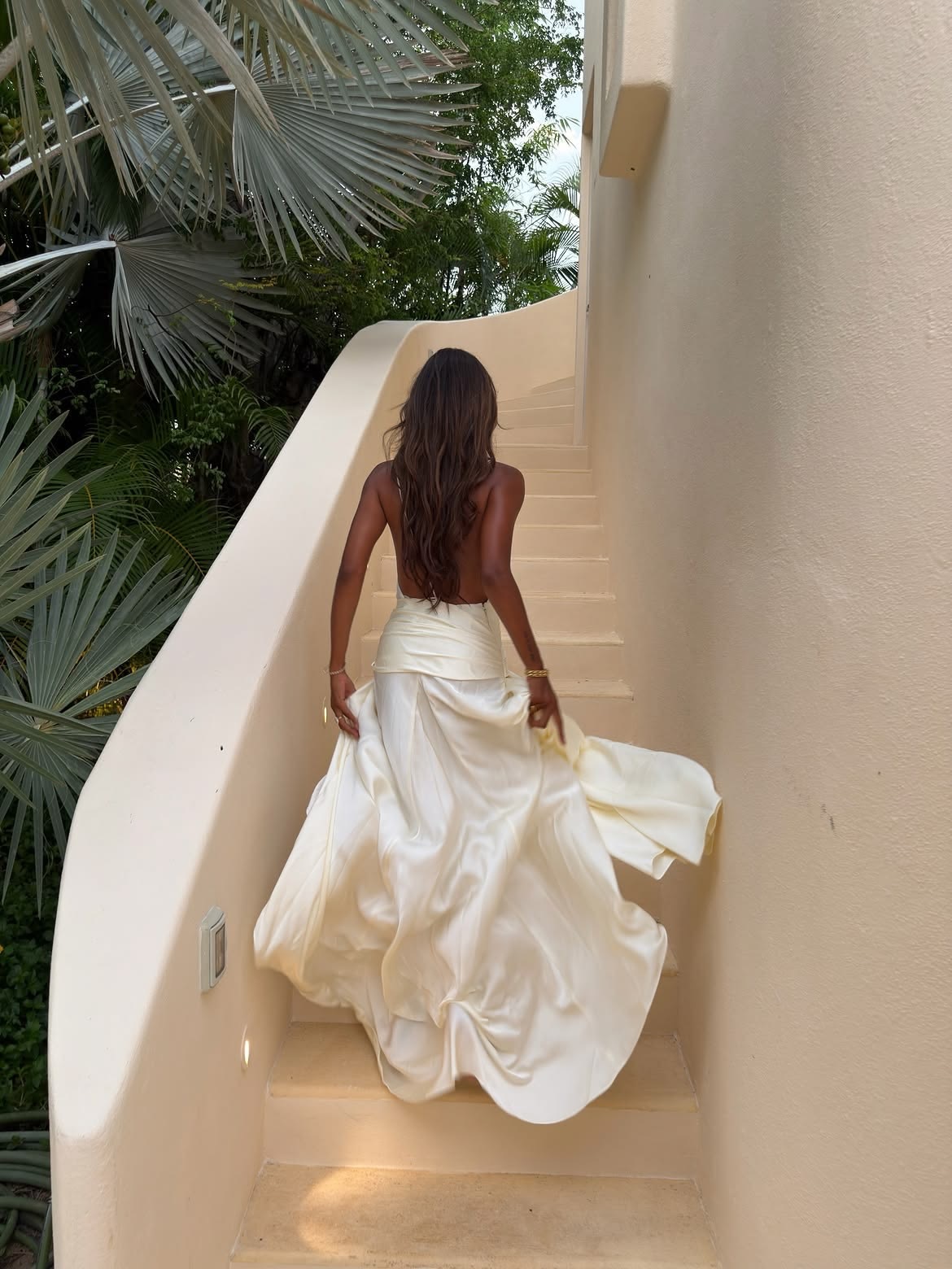 Woman in a flowing white dress ascending sculptural stairs