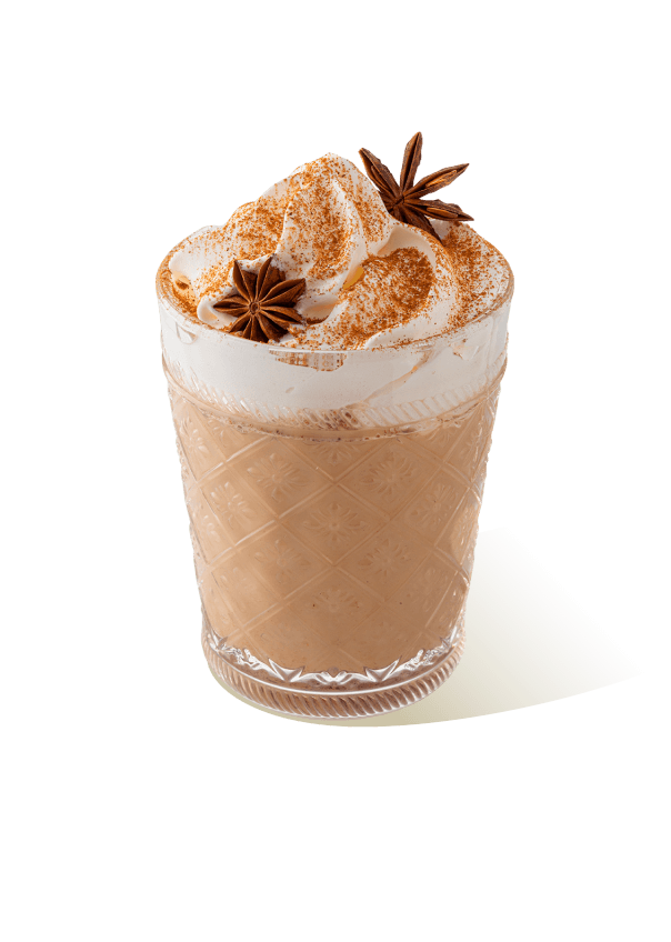 Chai latte in a glass with whipped cream, cinnamon powder and star anise, prepared using The Base Beverage chai latte powder