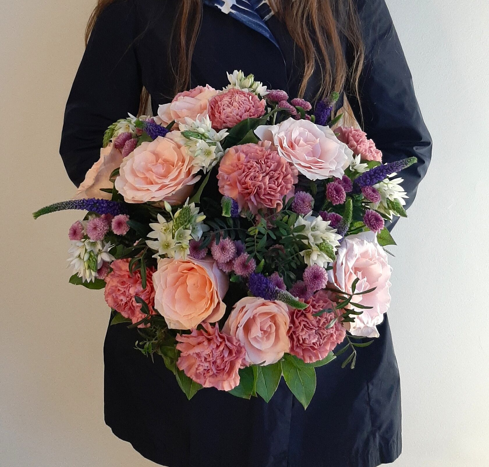 a lush mixed bouquet in soft peach and pinkish-lilac tones