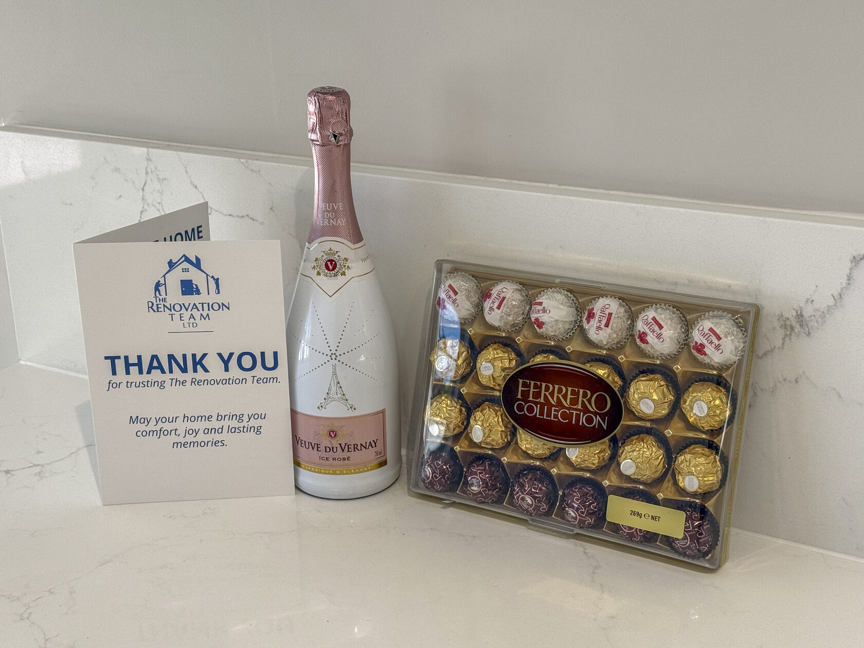 Thank-you card, sparkling wine and chocolates displayed on a kitchen worktop