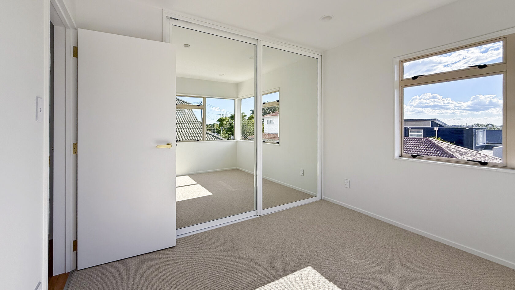 St Heliers bedroom with large windows, new carpet and mirrored sliding wardrobe doors.