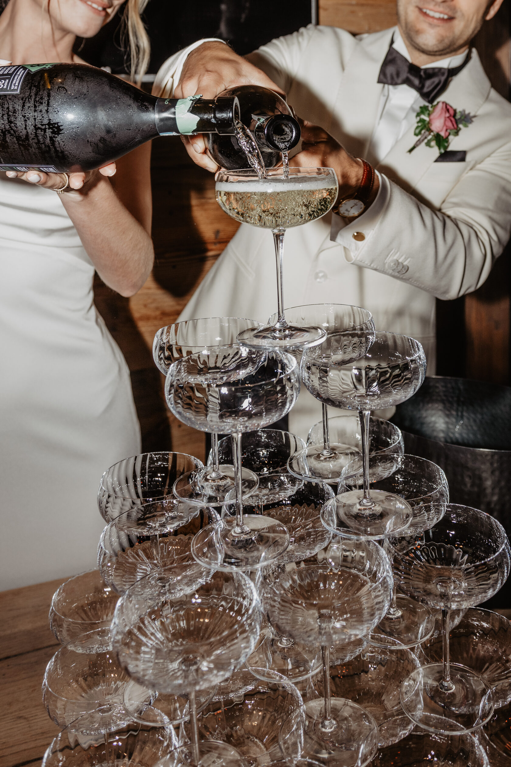 Champagne being poured into a tower of coupe glasses during the wedding celebration, close-up