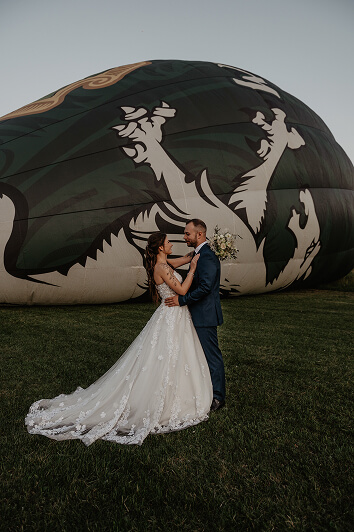 Bride and groom embracing in front of a hot air balloon — creative mountain wedding moment