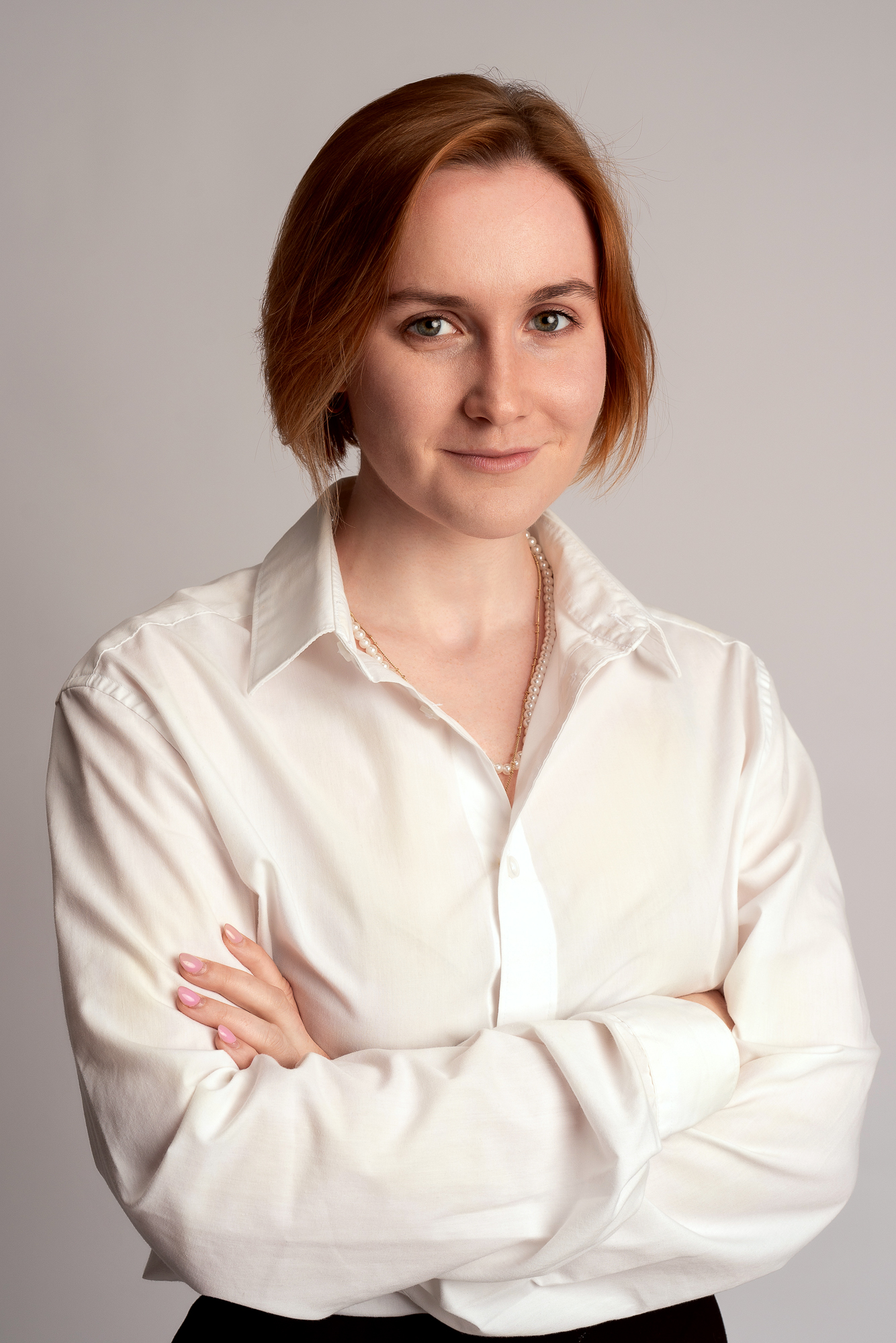 Businessportrait einer Frau in weißer Bluse vor einem hellen Hintergrund