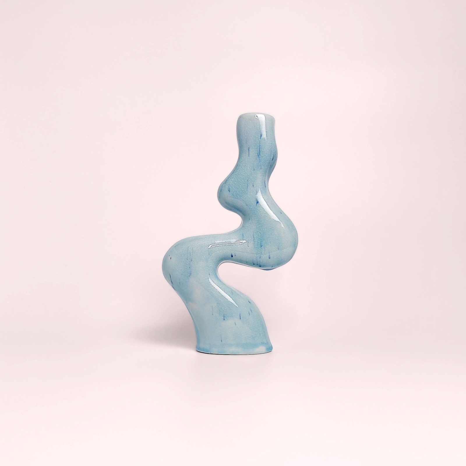 Unique handmade sculptural ceramic candle holder featuring a flowing wavy form and glossy blue glaze, designed for a single tall candle