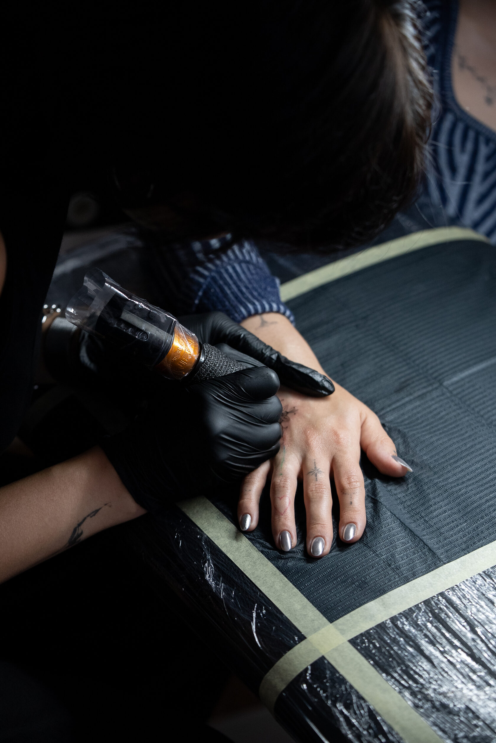 Tattoo-Artist mit Maschine bei der Arbeit an einer Hand im Brennnessel Studio