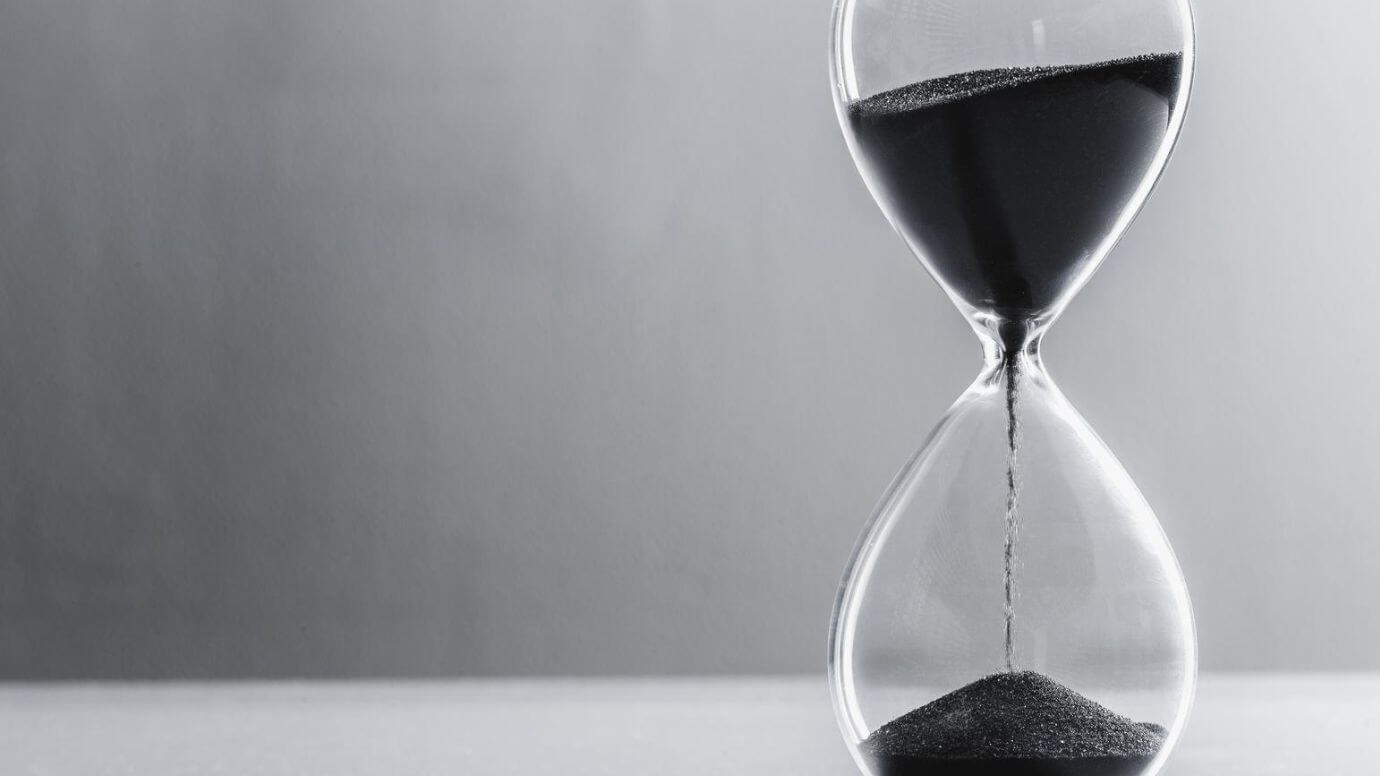 Grayscale image of an hourglass with sand flowing through its narrow center