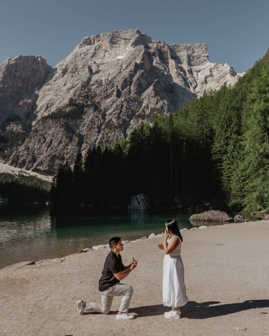 Surprise proposal by alpine lake Lago di Braies in Dolomites — emotional engagement photography in the mountains