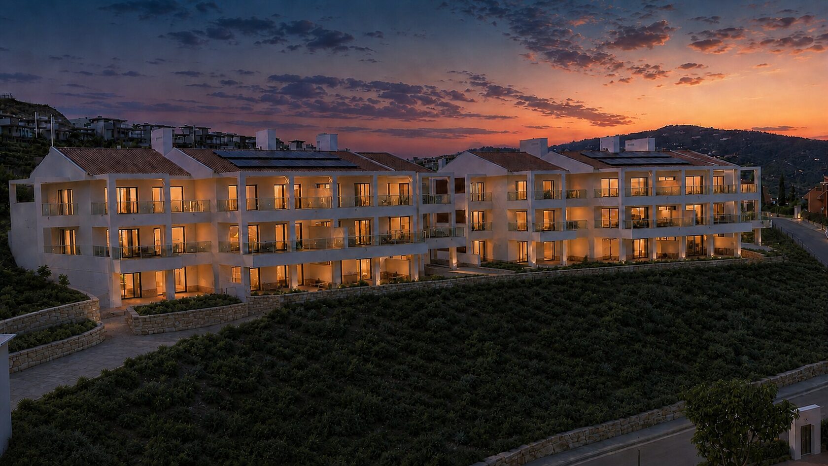 The apartment blocks lit at dusk above the Benahavís hills