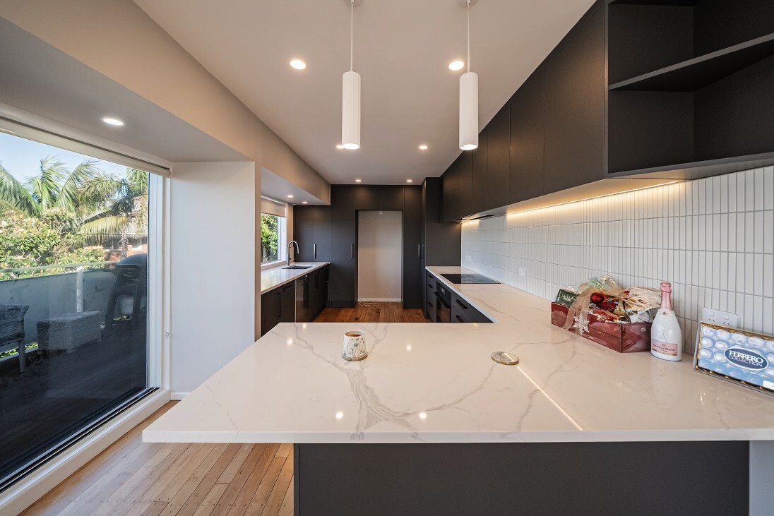 Renovated Glenfield kitchen with dark cabinetry, a light stone island and timber flooring