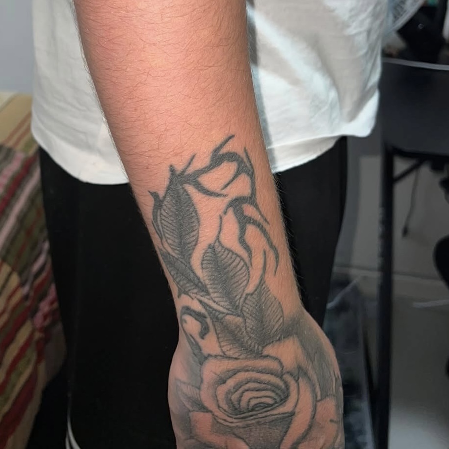 Altes florales Tattoo mit Rose am Unterarm vor dem Cover-Up