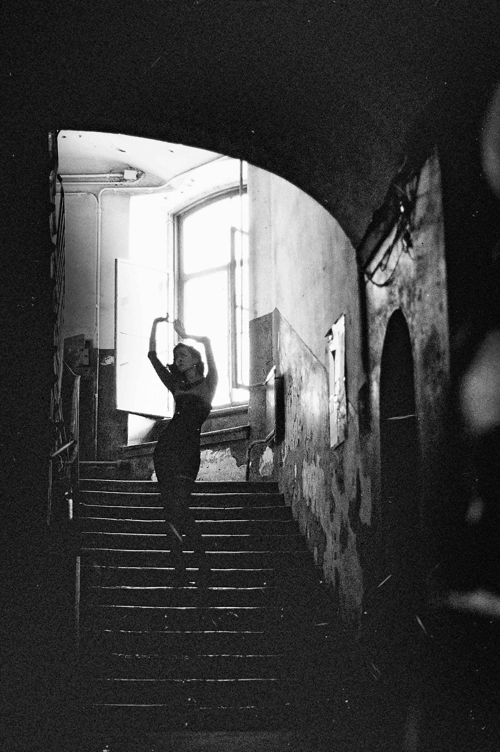 Schwarz-Weiß-Portrait einer Frau auf einer Treppe im Gegenlicht