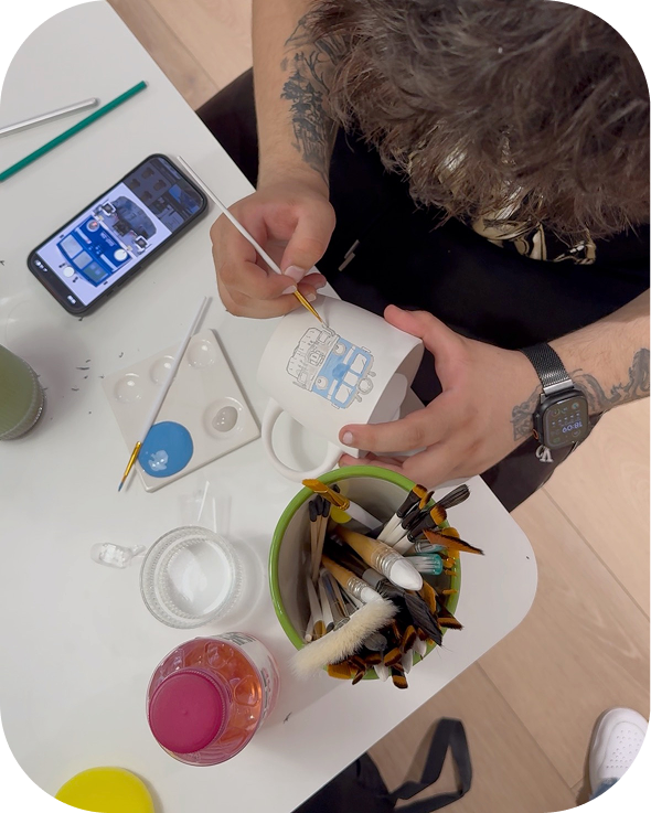 Painting ceramics with a brush — a paint palette and inspiration on a phone next to it