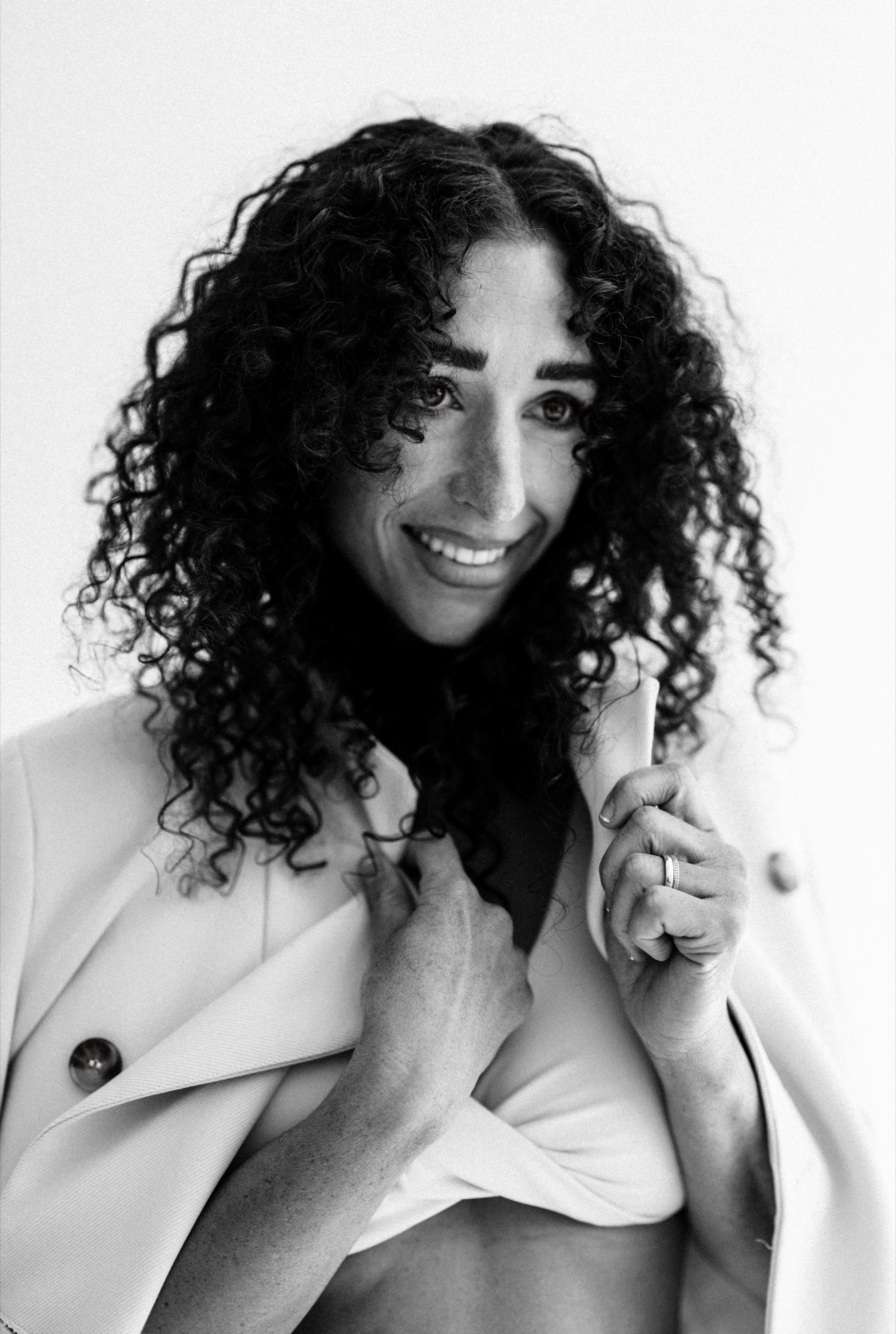 Lächelndes Model mit Locken und hellem Blazer, Schwarz-Weiß-Porträt