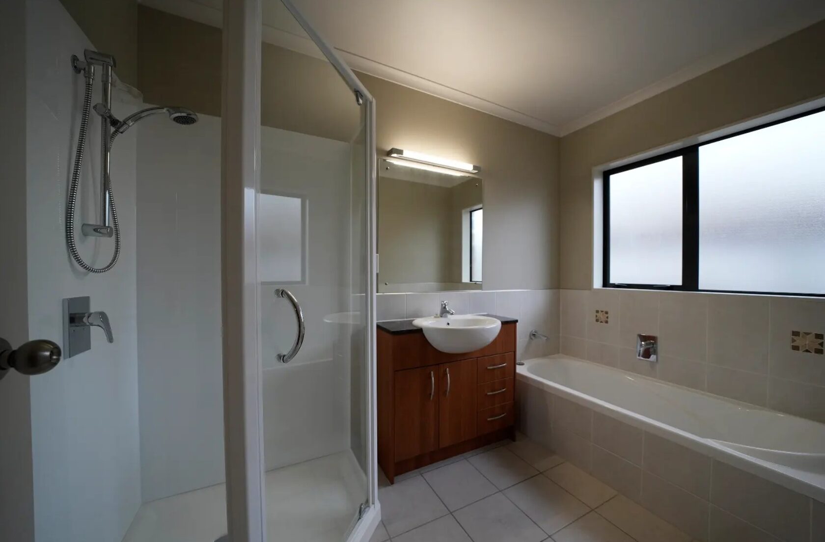 Before: Original family bathroom with enclosed shower, timber vanity, bathtub and frosted window