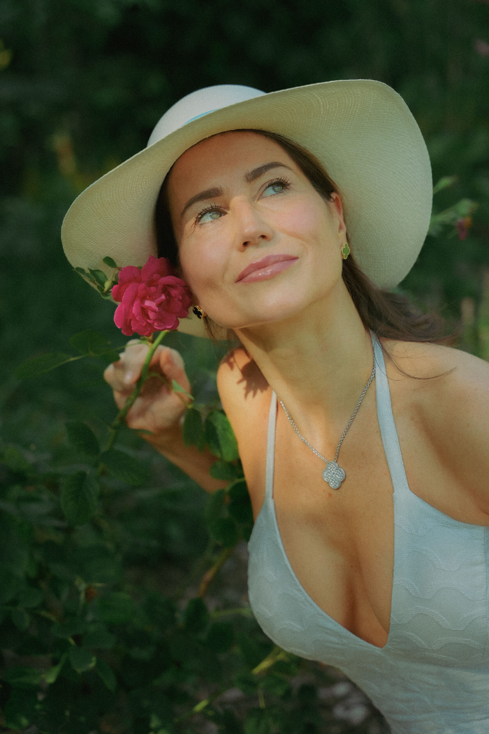 Editorial portrait of a woman wearing a hat and holding a flower