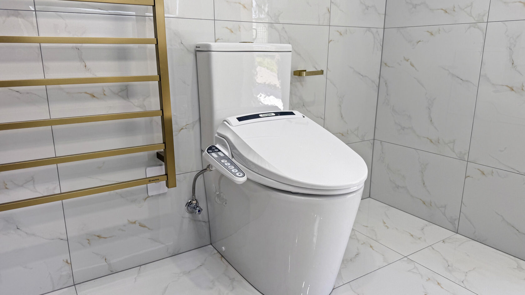 Smart bidet toilet and brushed brass heated towel rail in a St Heliers bathroom.