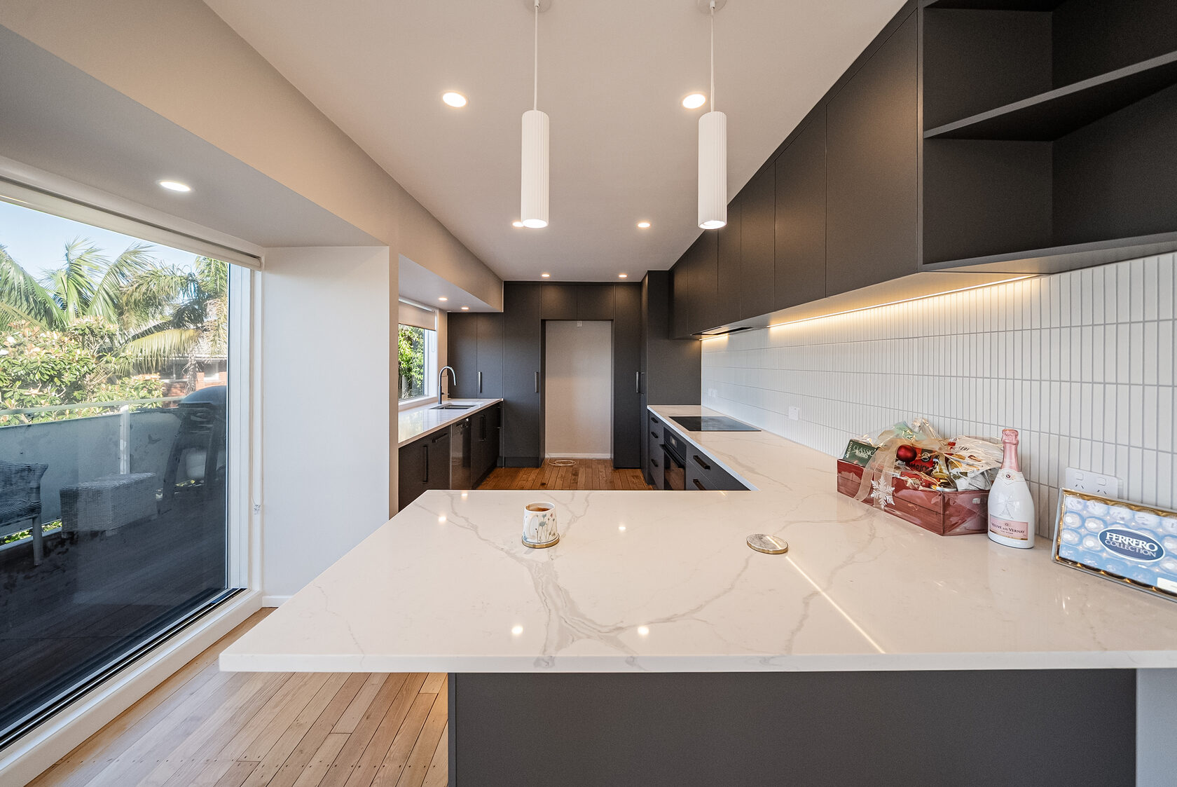Renovated Glenfield kitchen with dark cabinetry, pale benchtops and pendant lighting