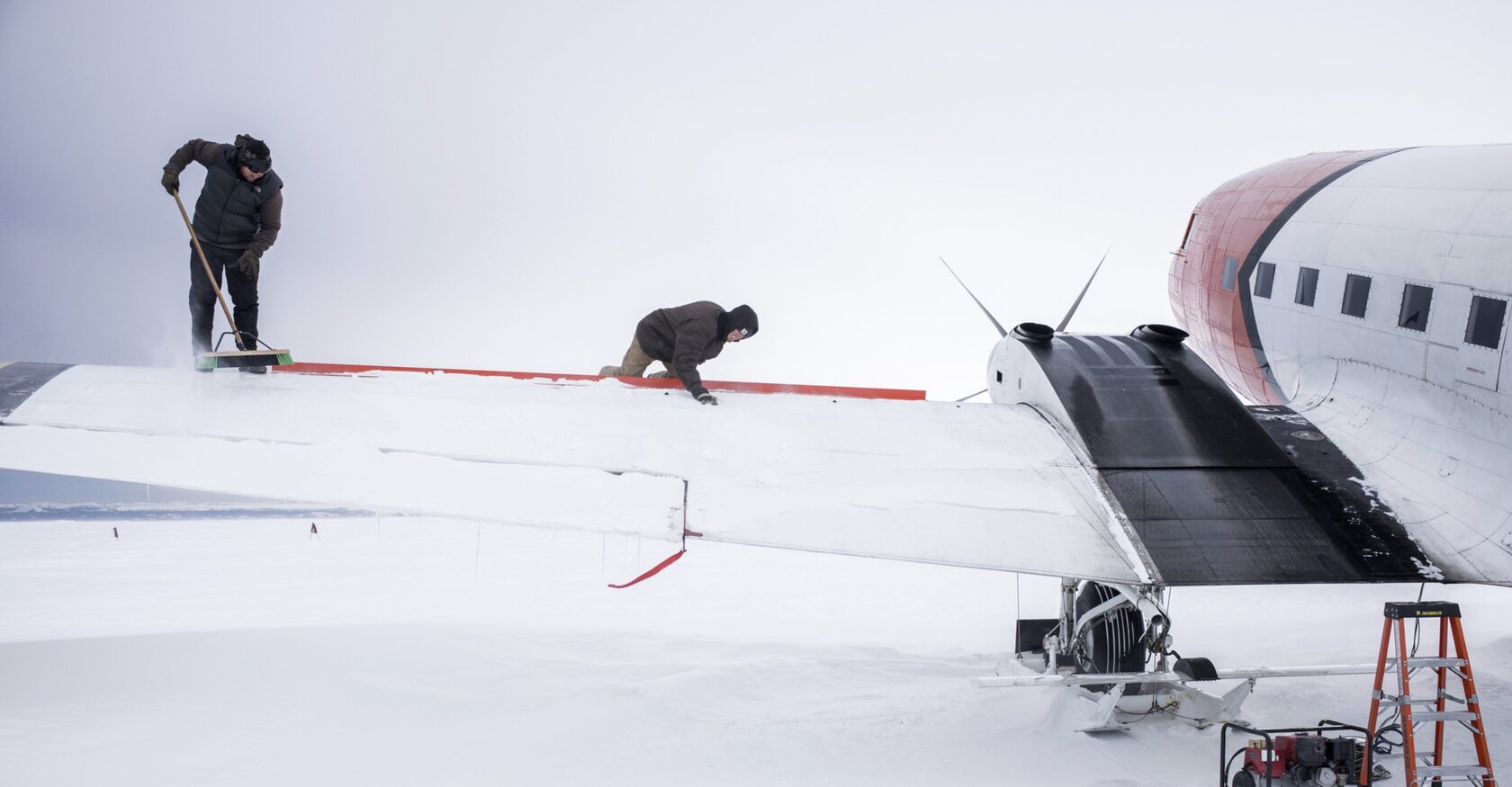 Crew clearing snow from an aircraft wing in Antarctica
