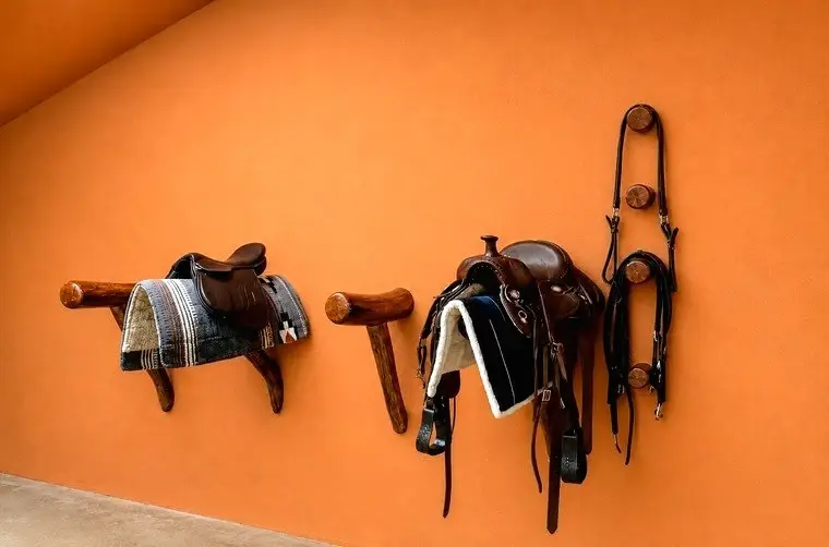 Premium equestrian tack displayed on handcrafted hardwood saddle racks inside The Tack Room at Vonfidel Ranch in Sri Lanka.