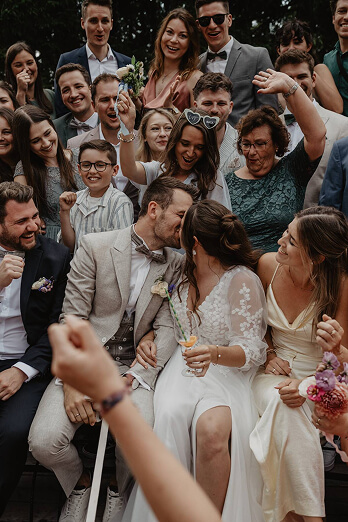 Bride and groom kissing surrounded by cheering guests — joyful mountain wedding celebration near Zugspitze, in Austria