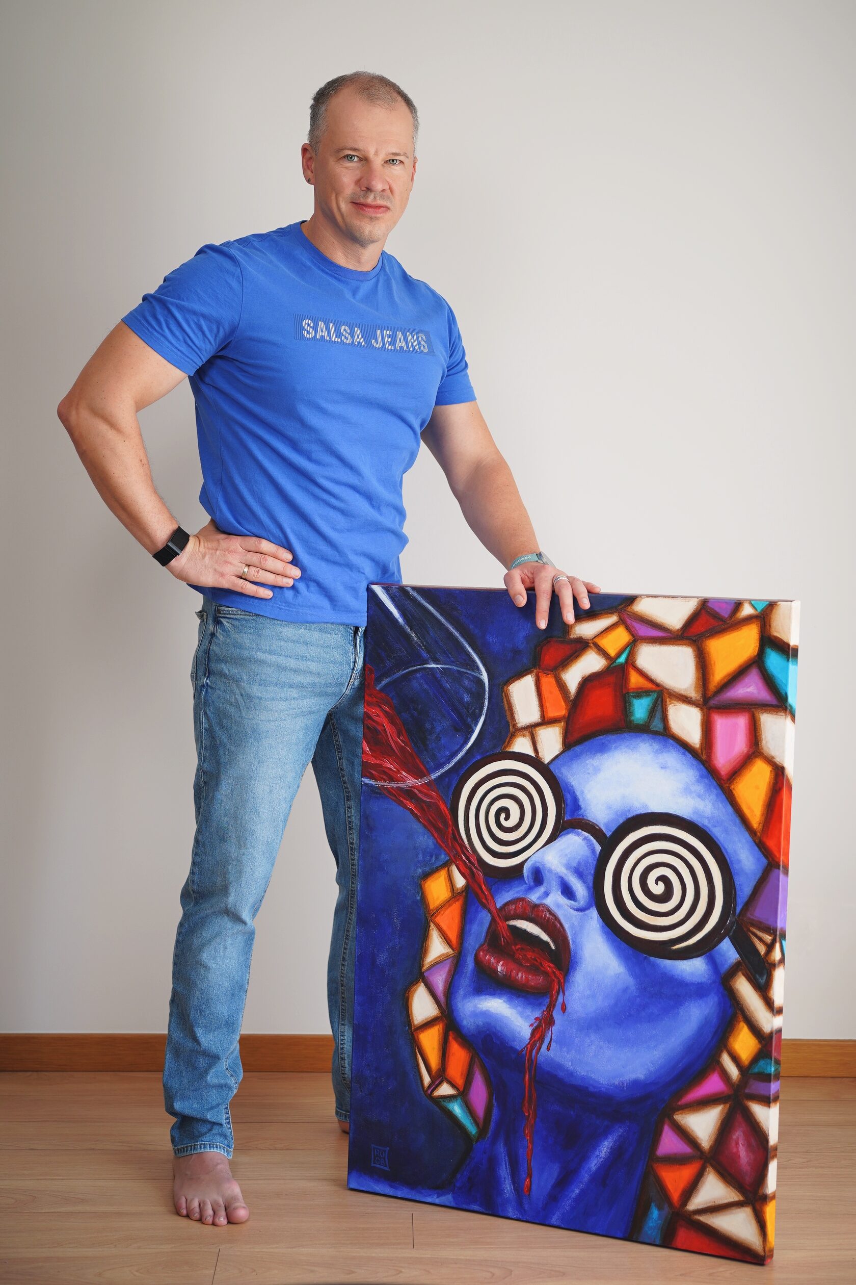 The artist in his studio, holding a finished acrylic painting
