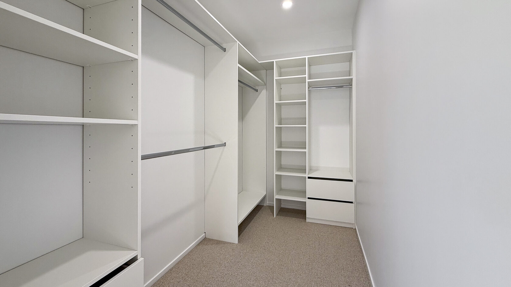 Custom walk-in wardrobe with shelving, hanging rails and drawers in St Heliers.