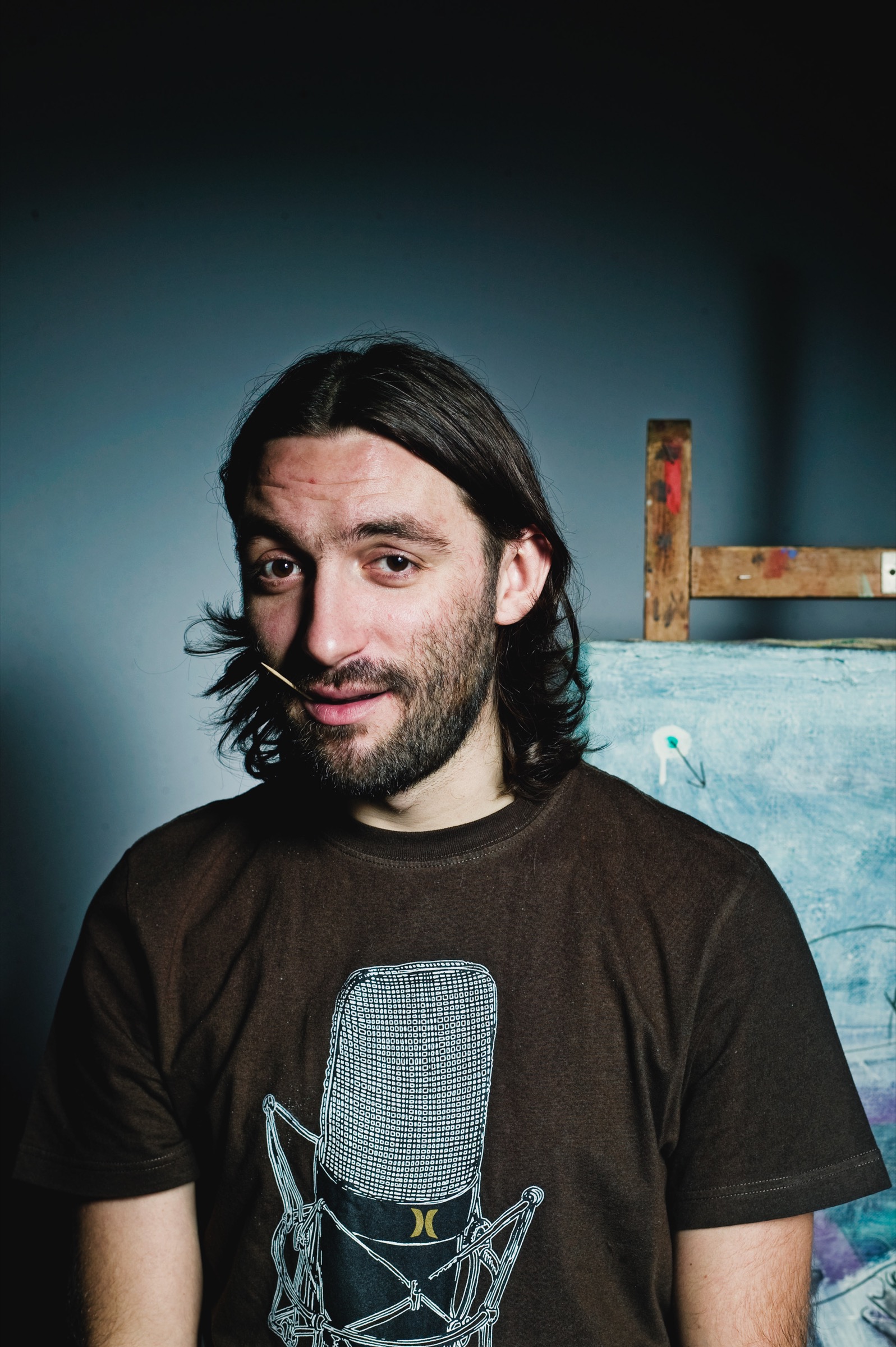 Farbportrait eines Mannes vor blauem Hintergrund und einer Staffelei