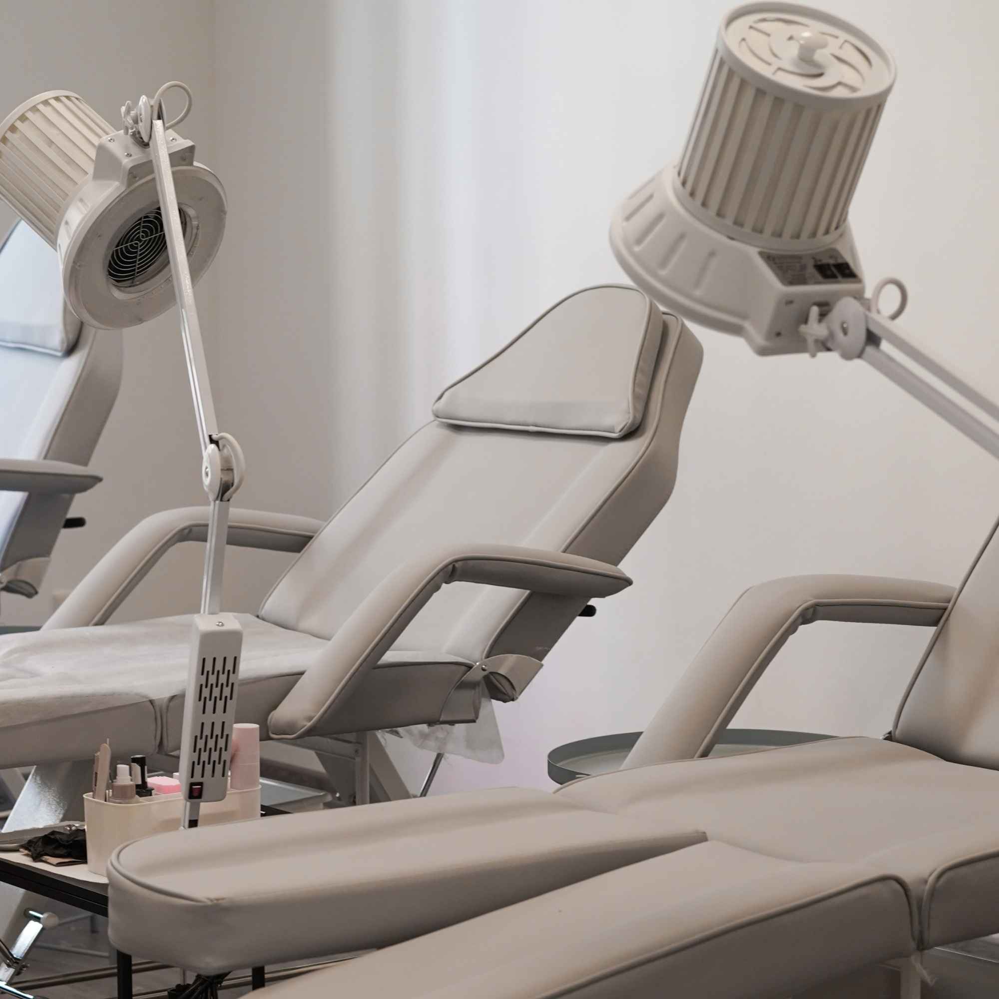 Světlé pracovní křesla a lampy v salonu Nail House