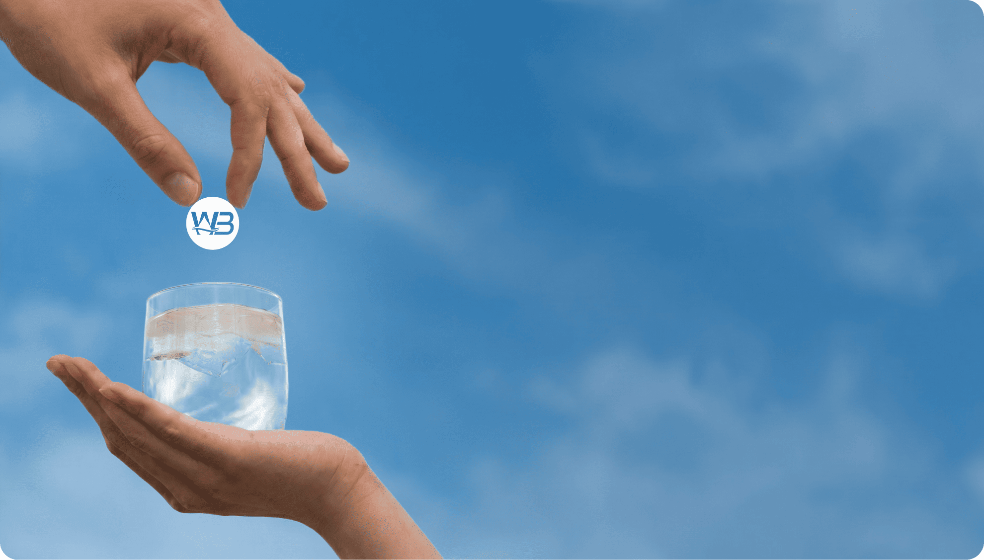 A glass of water held against a blue sky