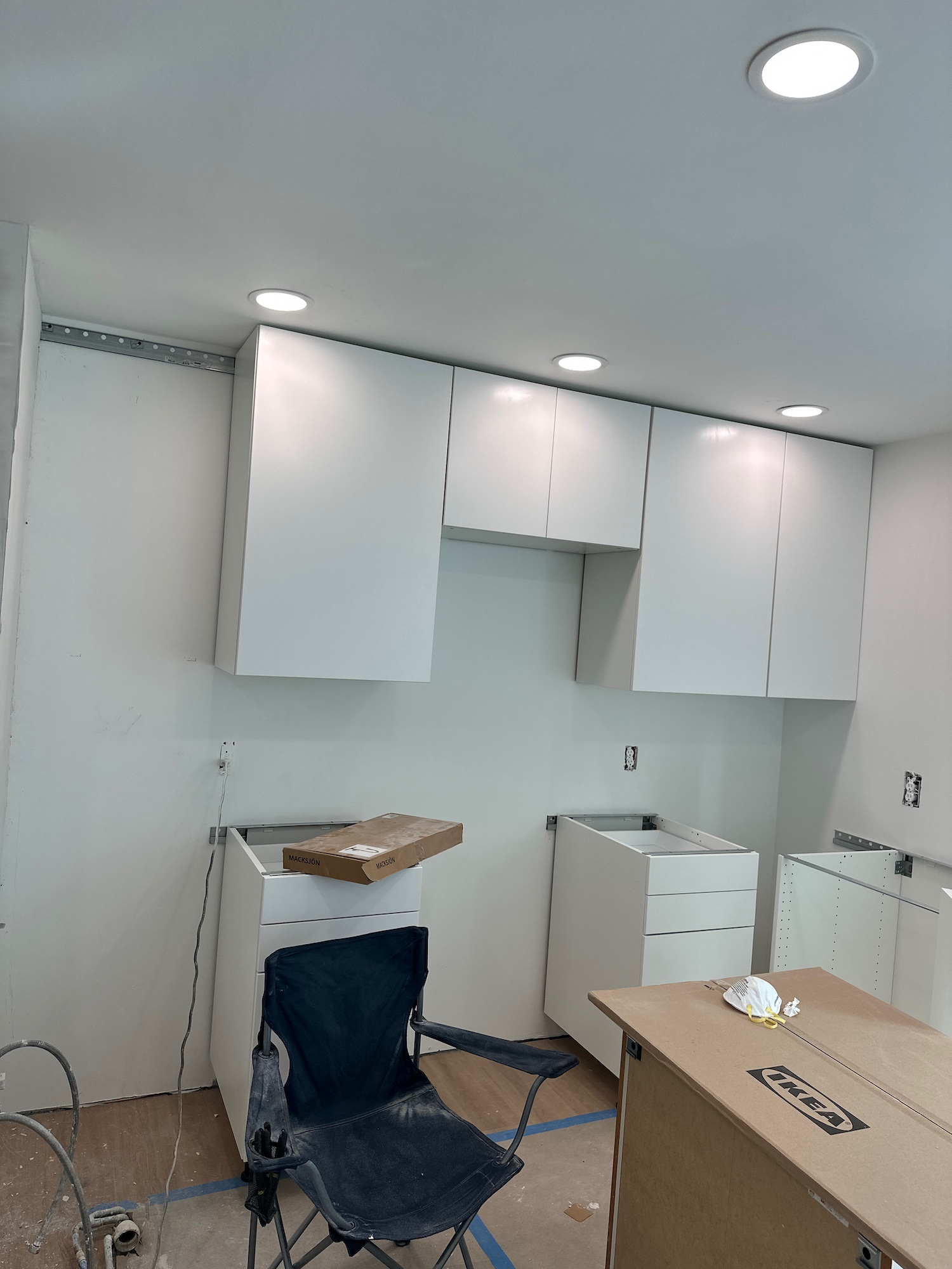 White kitchen cabinets being installed by Kir Remodeling, with work surfaces protected during the project