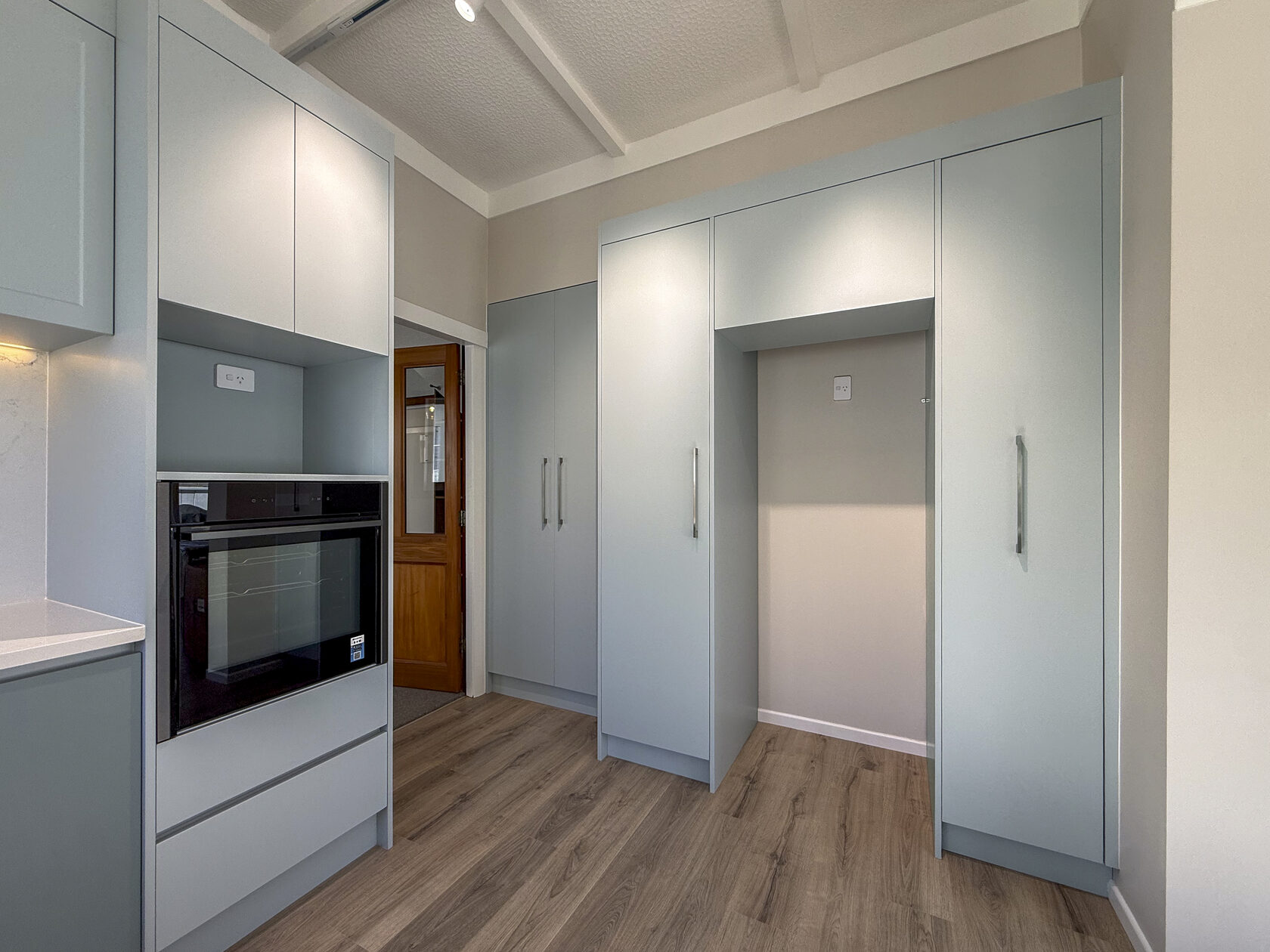 Built-in oven set into pale green kitchen cabinetry