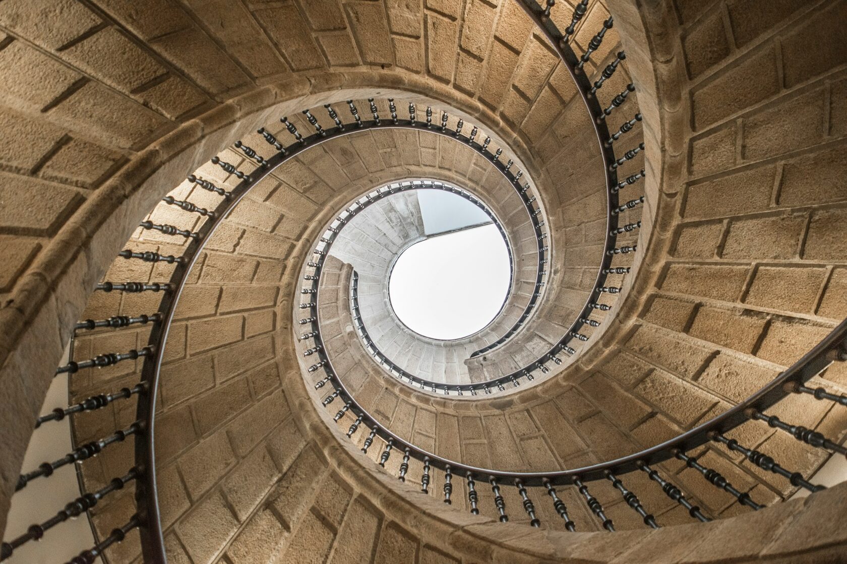 Looking down the mossy spiral staircase of the Initiation Well at Quinta da Regaleira in Sintra, in soft green light