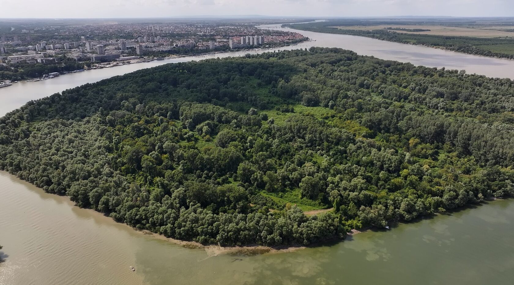 Pogled iz ptičje perspektive na Veliko Ratno ostrvo (ostrvo Velikog rata) u Beogradu, smešteno na ušću reke Save u Dunav. Močvarno močvarno područje prekriveno gustom šumom služi kao važno gradsko utočište za ptice i područje zaštite od poplava, kao i mesto dobrovoljnih subotnjaka sa kopnenim i brodskim timovima za očuvanje jedinstvene biološke raznolikosti