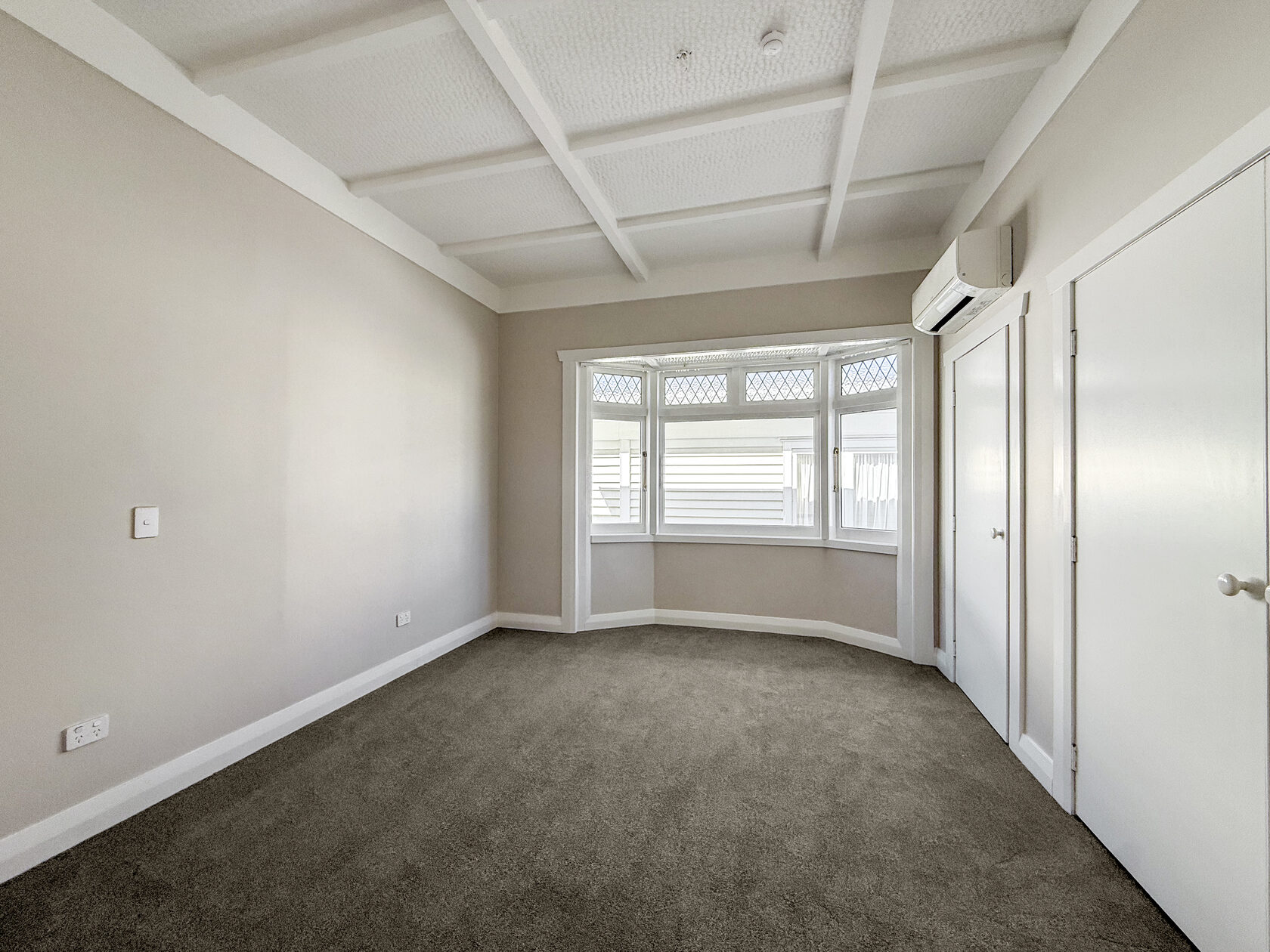 Carpeted room with a bay window and light walls in the Epsom bungalow